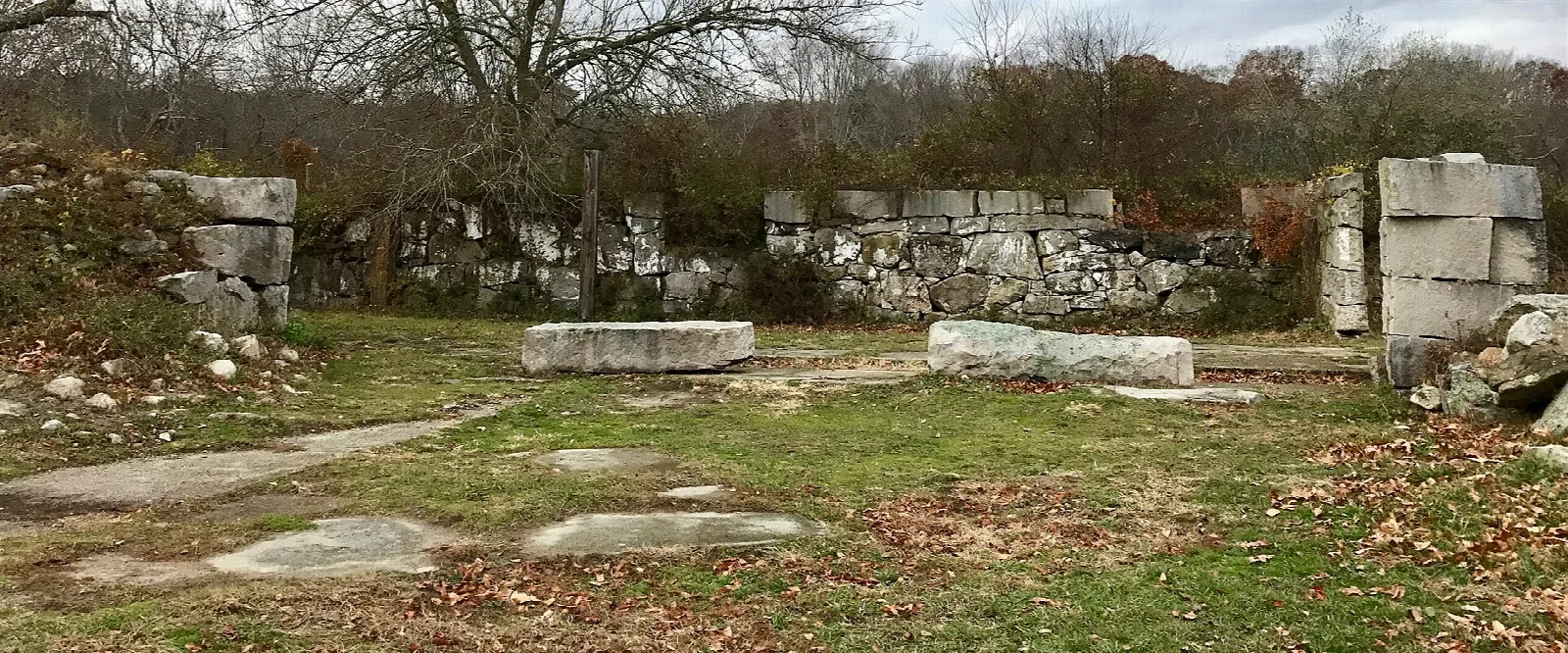 Old stone walls and foundation ruins in a grassy clearing