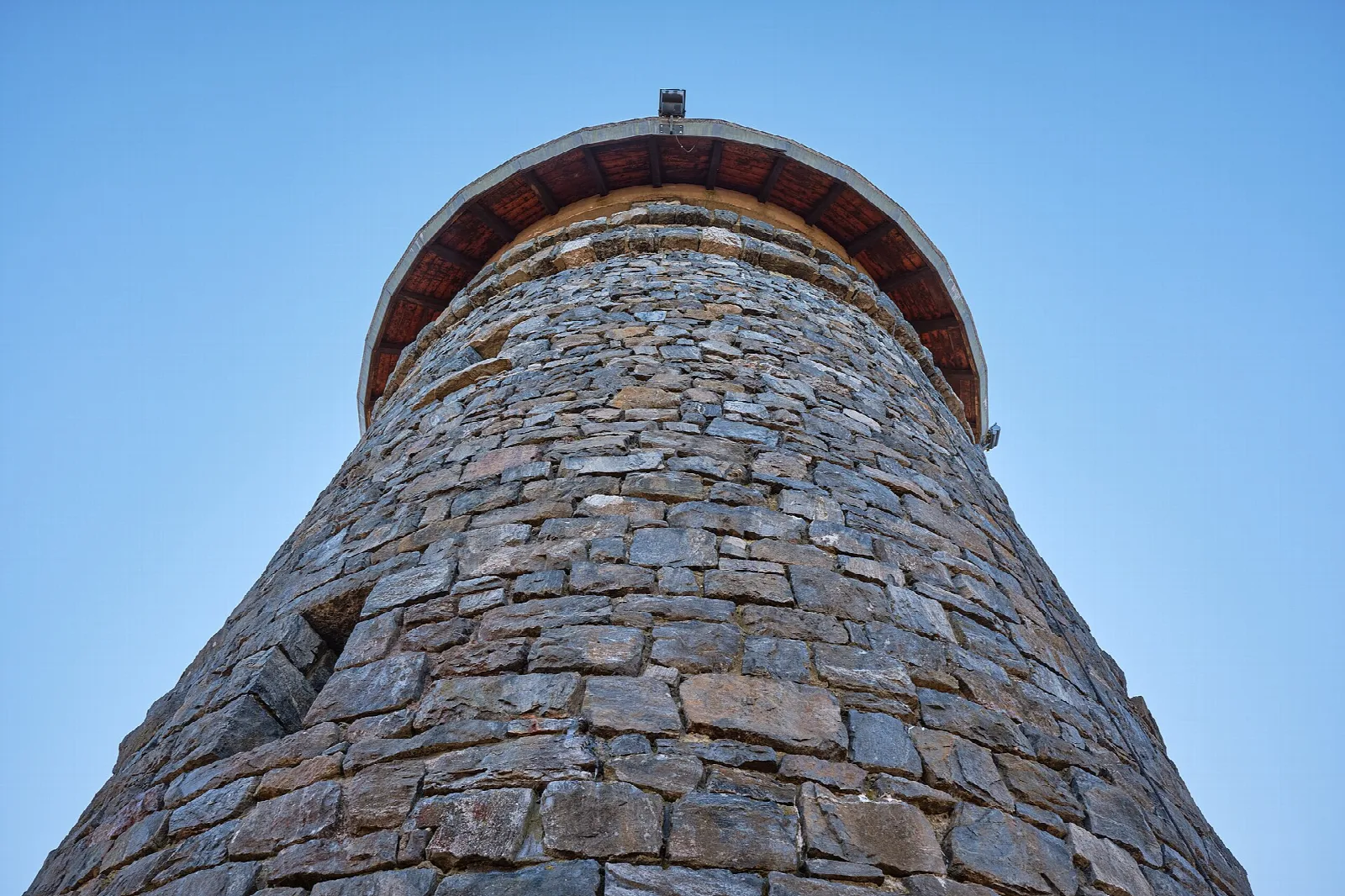 Looking up at a round stone tower against blue sky