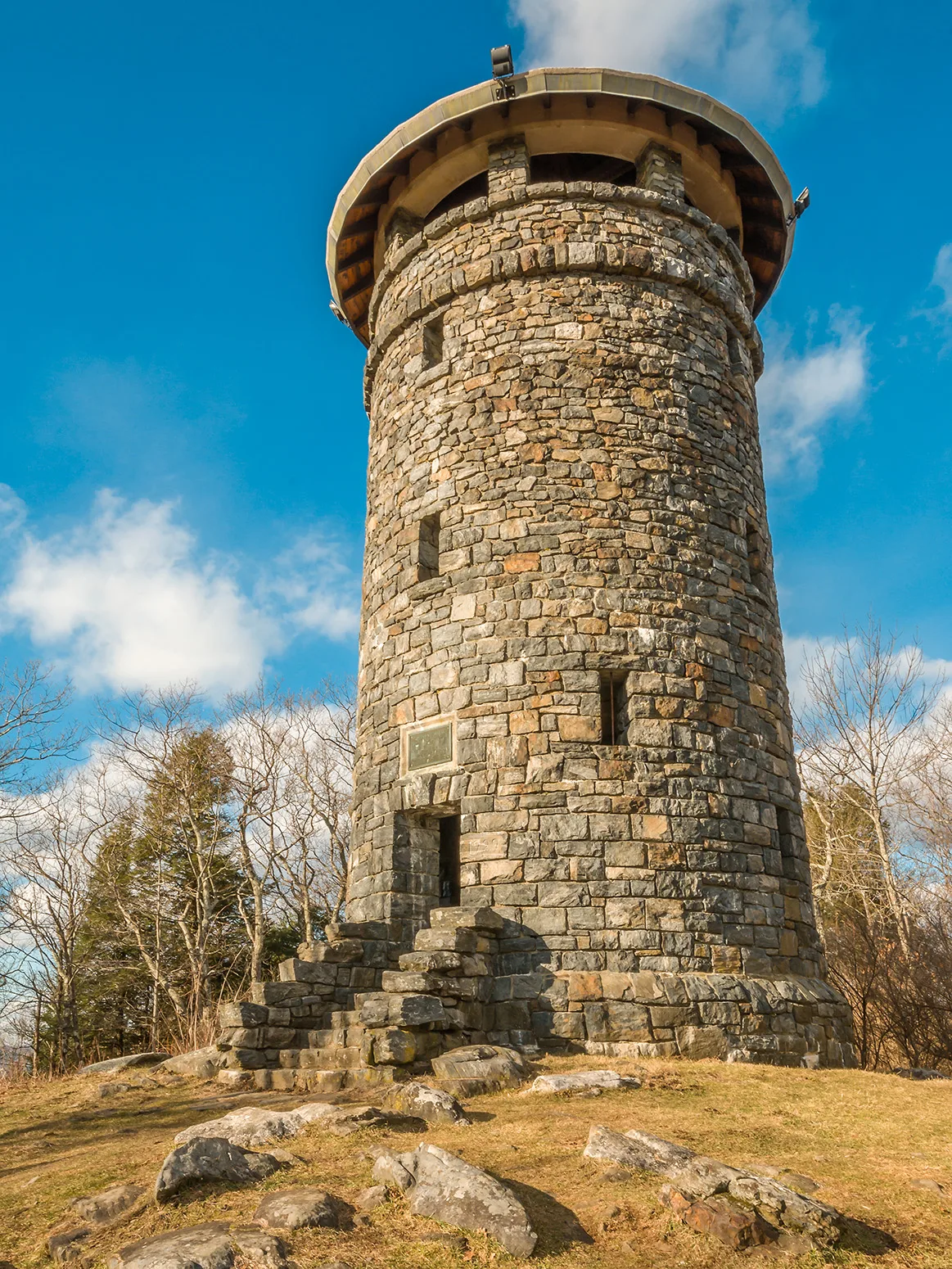 Round stone tower on a rocky summit under blue sky