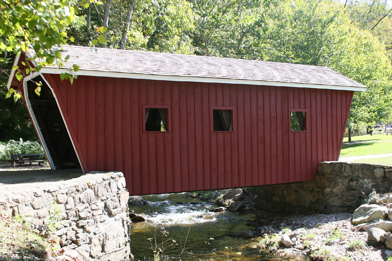 Red covered bridge over a rocky stream