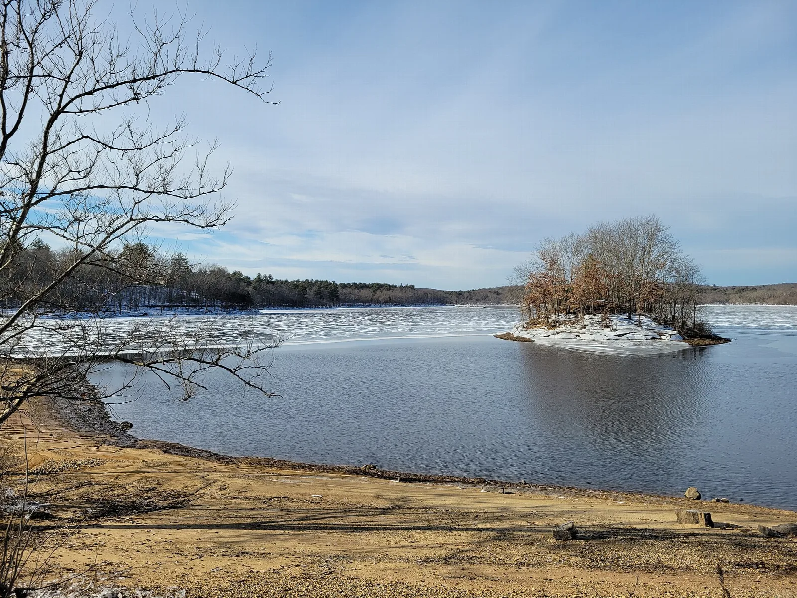 Frozen lake with a small island and sandy beach