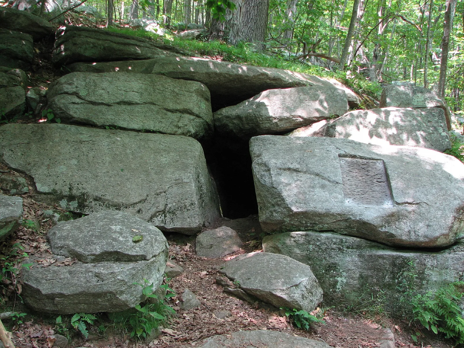 Pile of large boulders with a dark opening