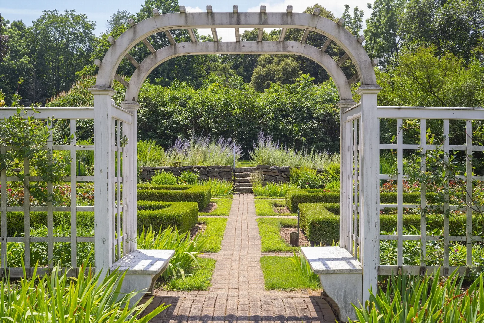 White arbor over a brick path in a garden