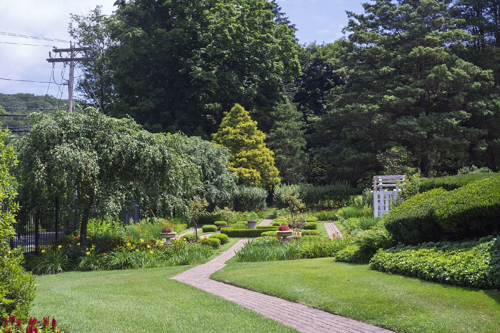 Formal garden with brick path, hedges and tall trees