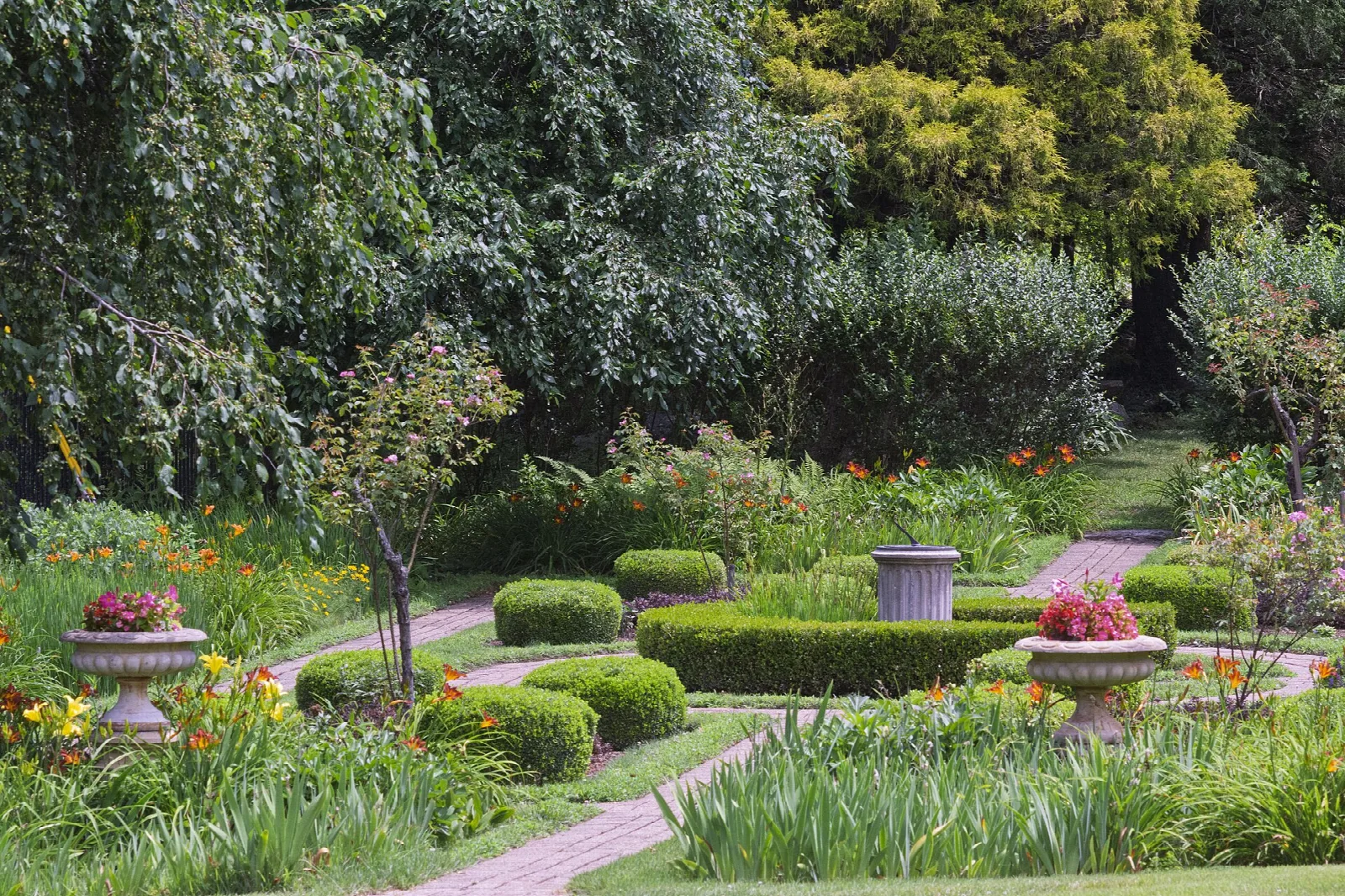 Garden beds with urns and a curving brick path