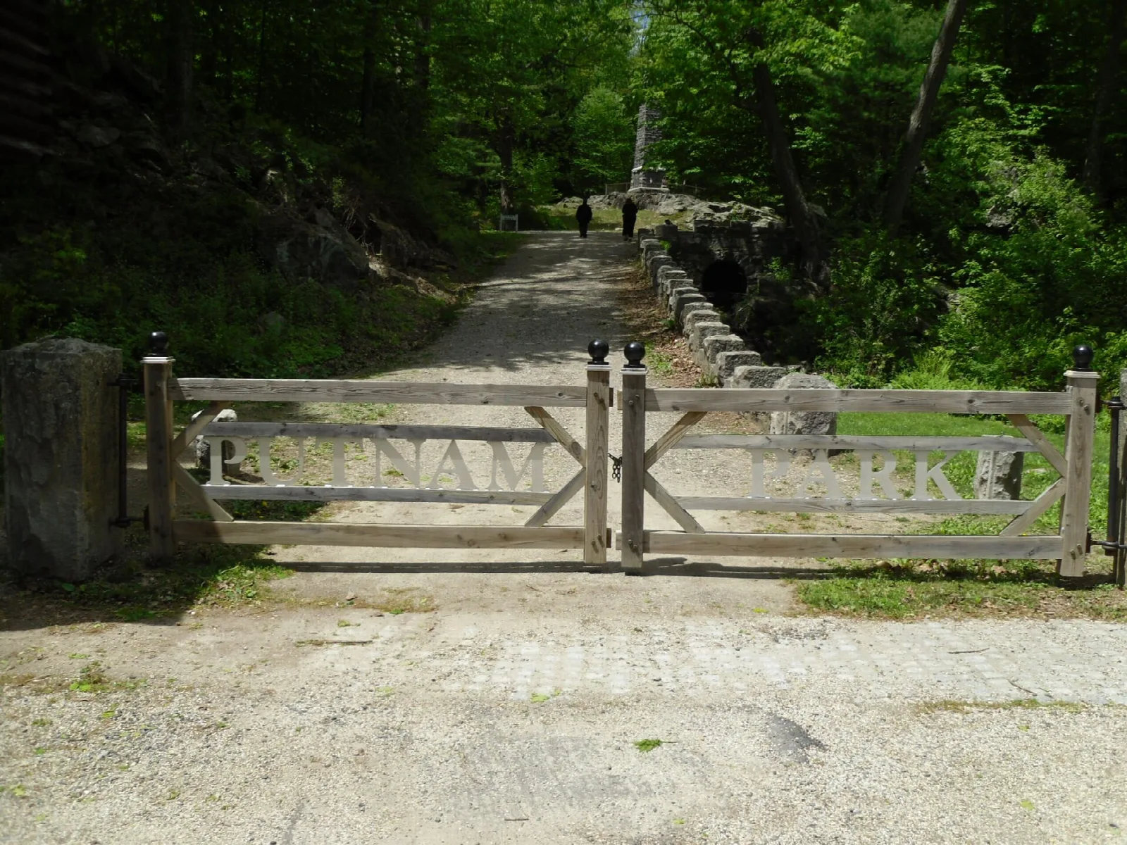 Wooden gate across a gravel path into the woods