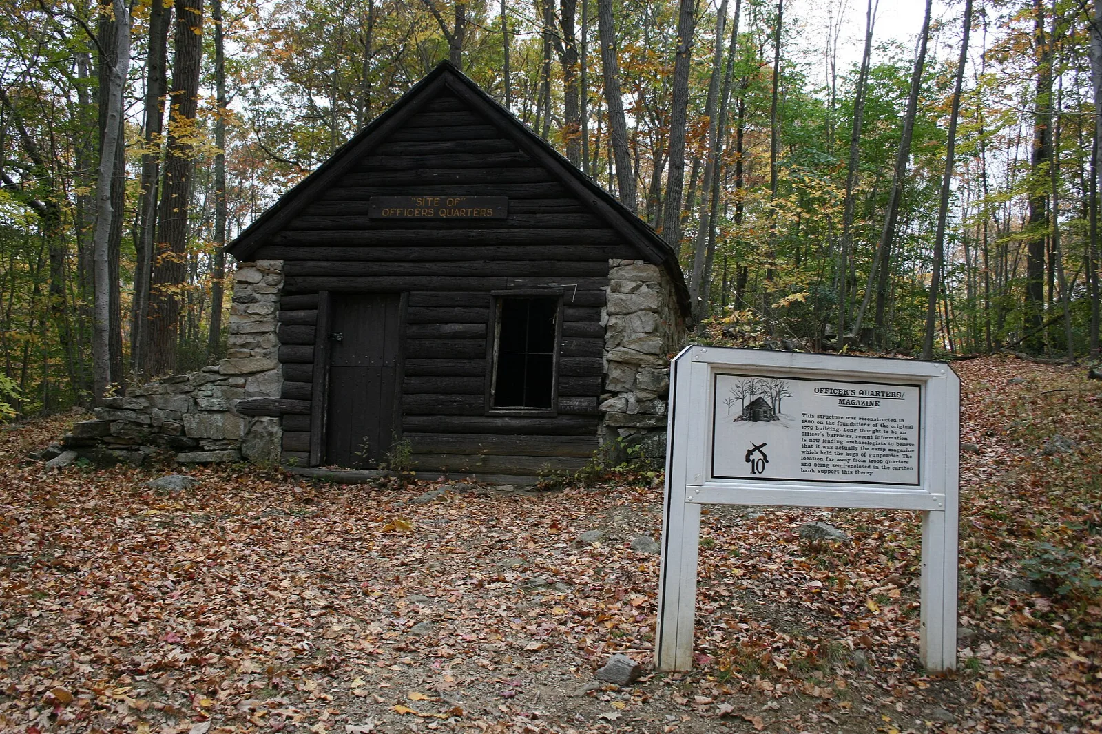 Small log hut with a stone base and a sign