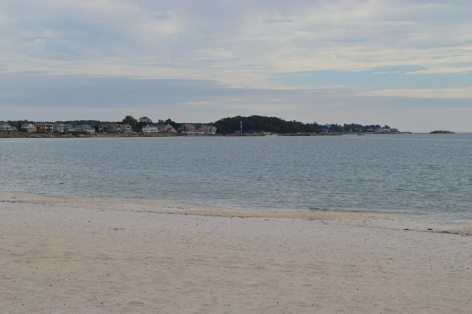 Wide beach and calm water with shoreline houses far off
