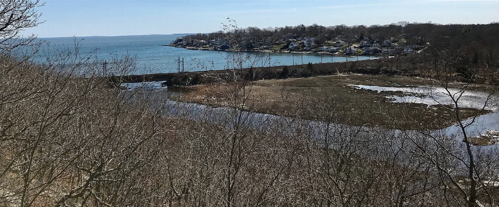 Tidal inlet and bridge seen from a bare hillside overlook