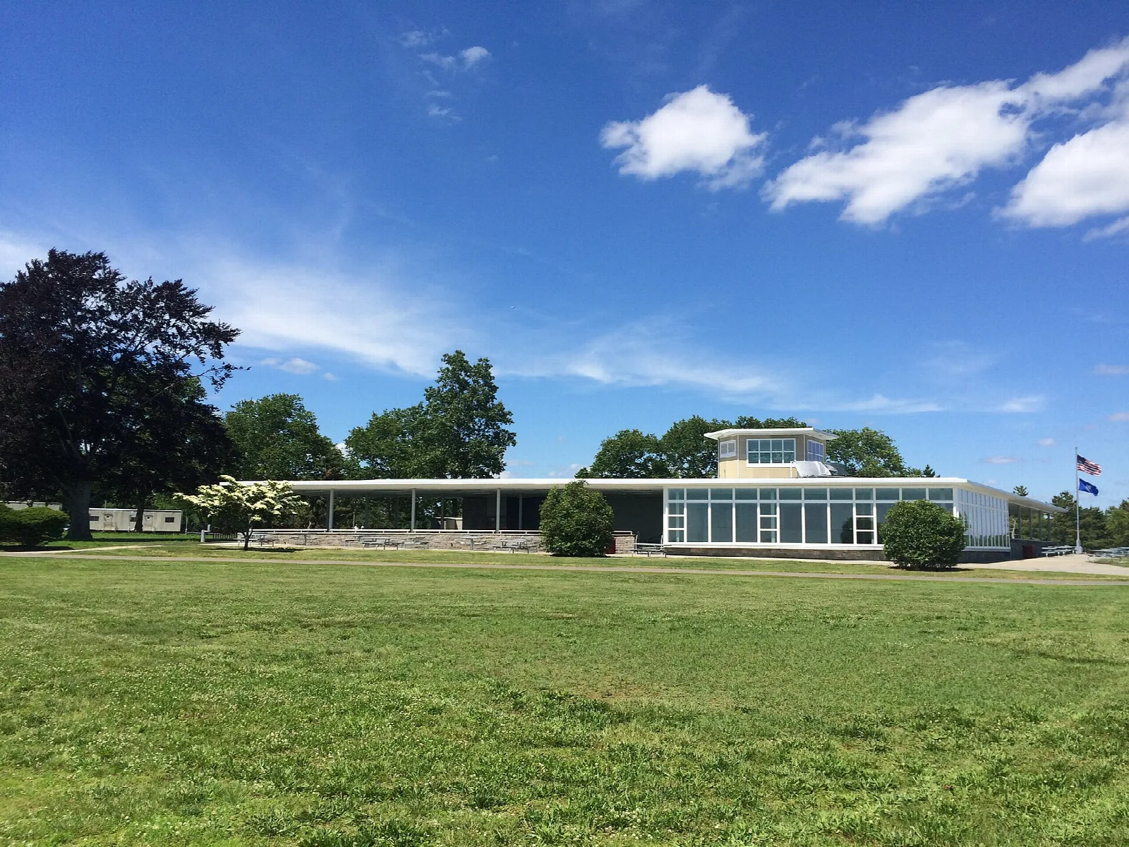 Low glass-walled building across a wide green lawn