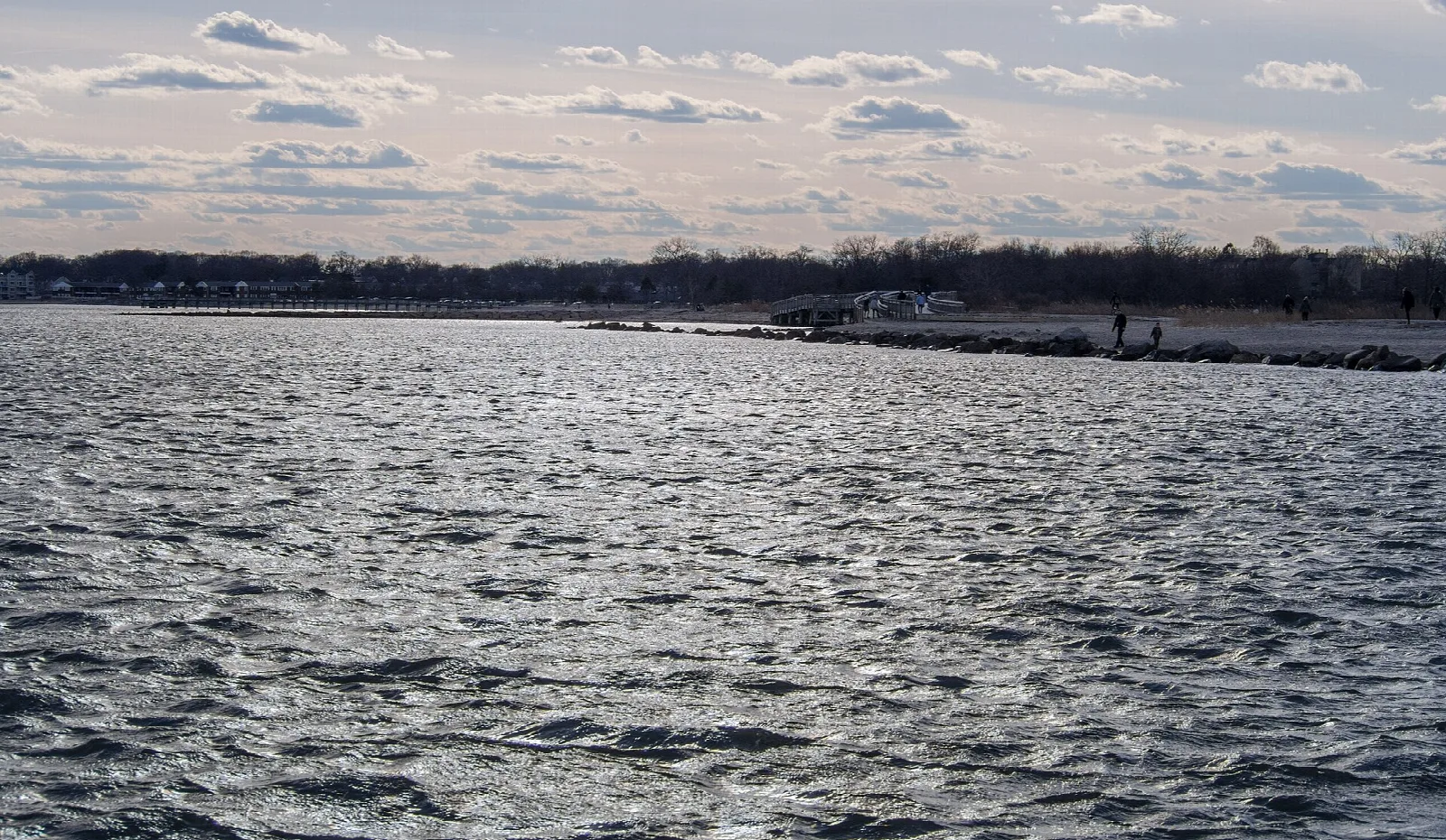 Rippled water along the shore under scattered clouds
