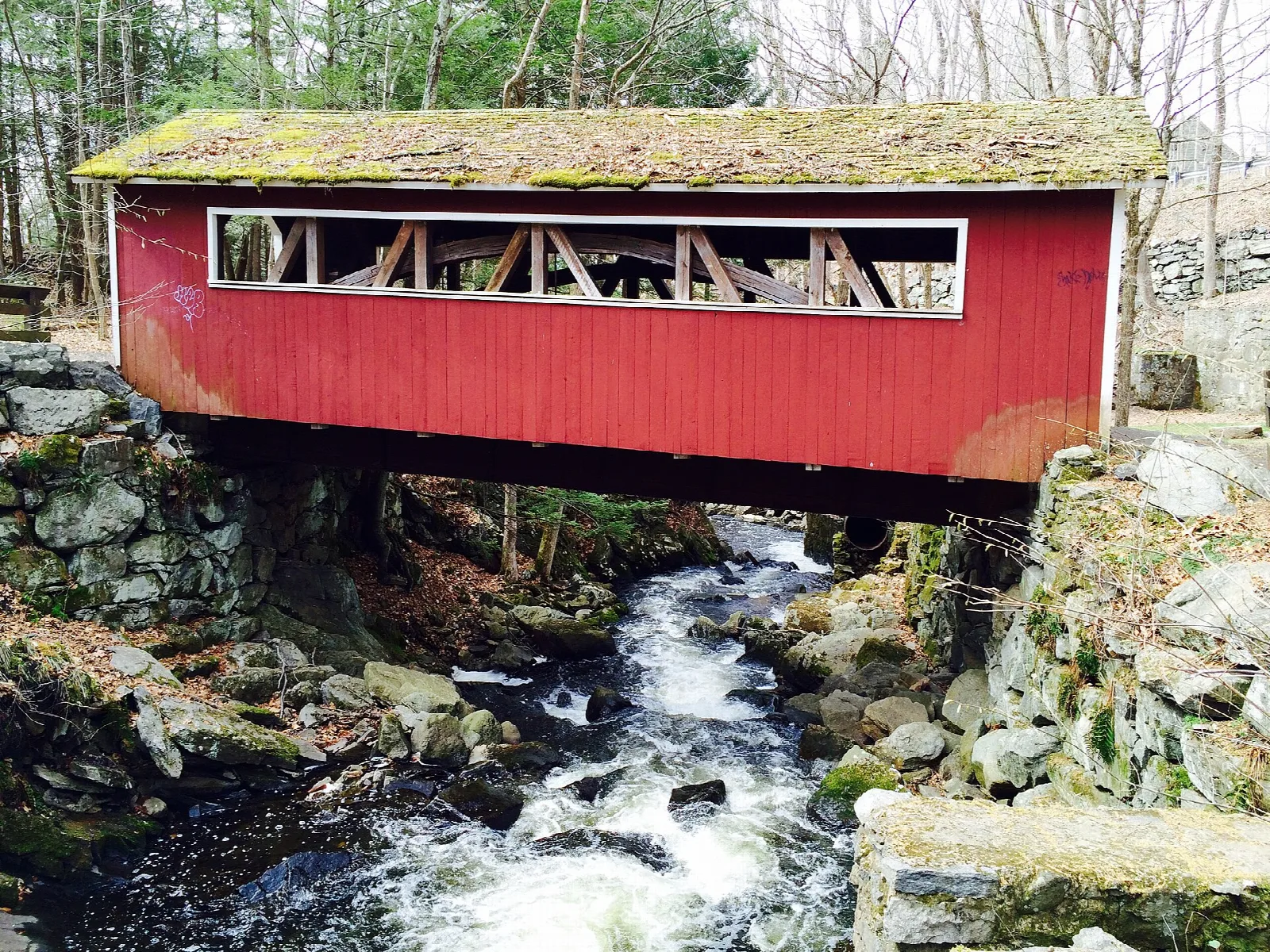 Red covered bridge over a rocky stream