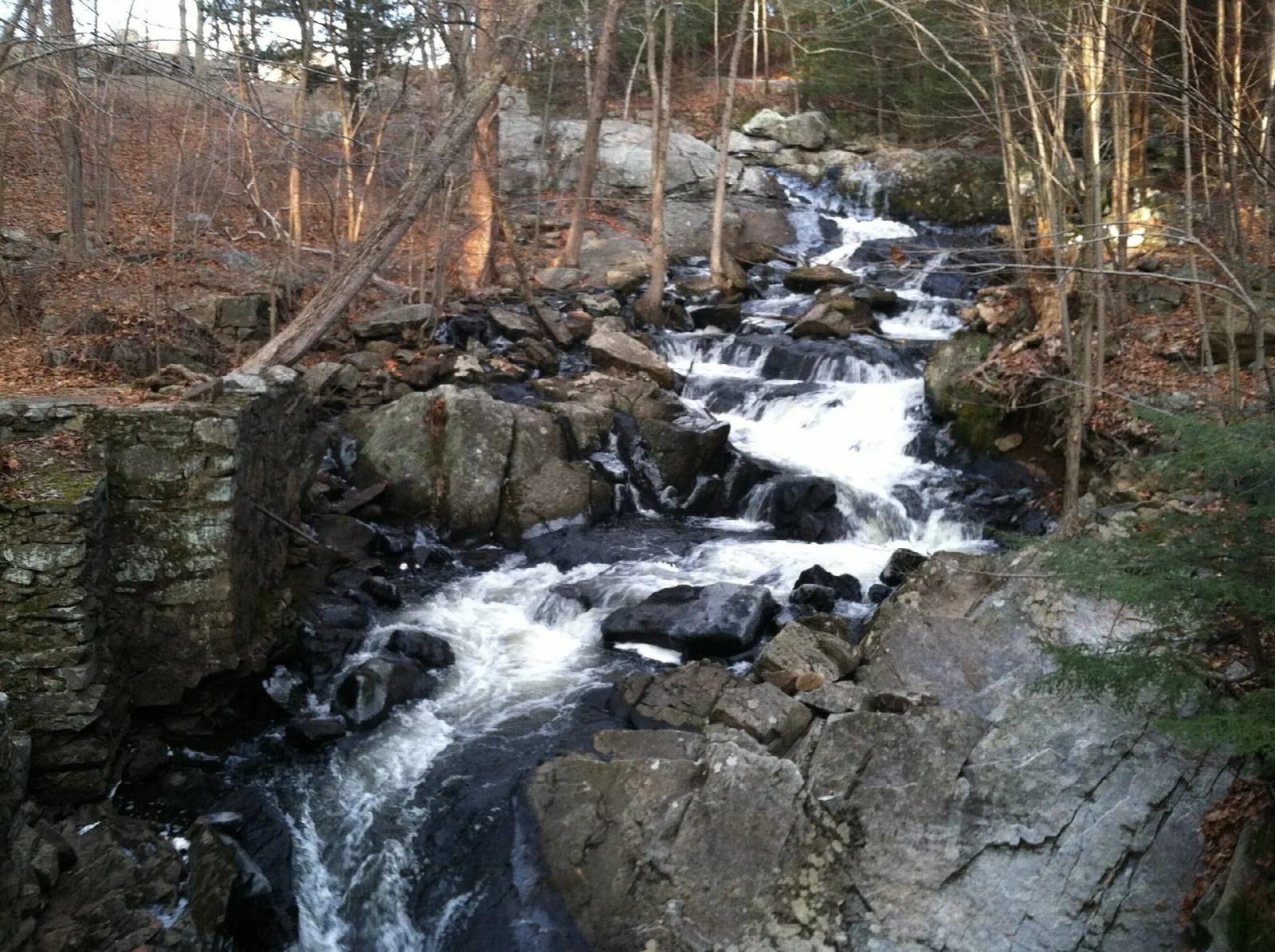 Stream tumbling over rocks beside an old stone wall