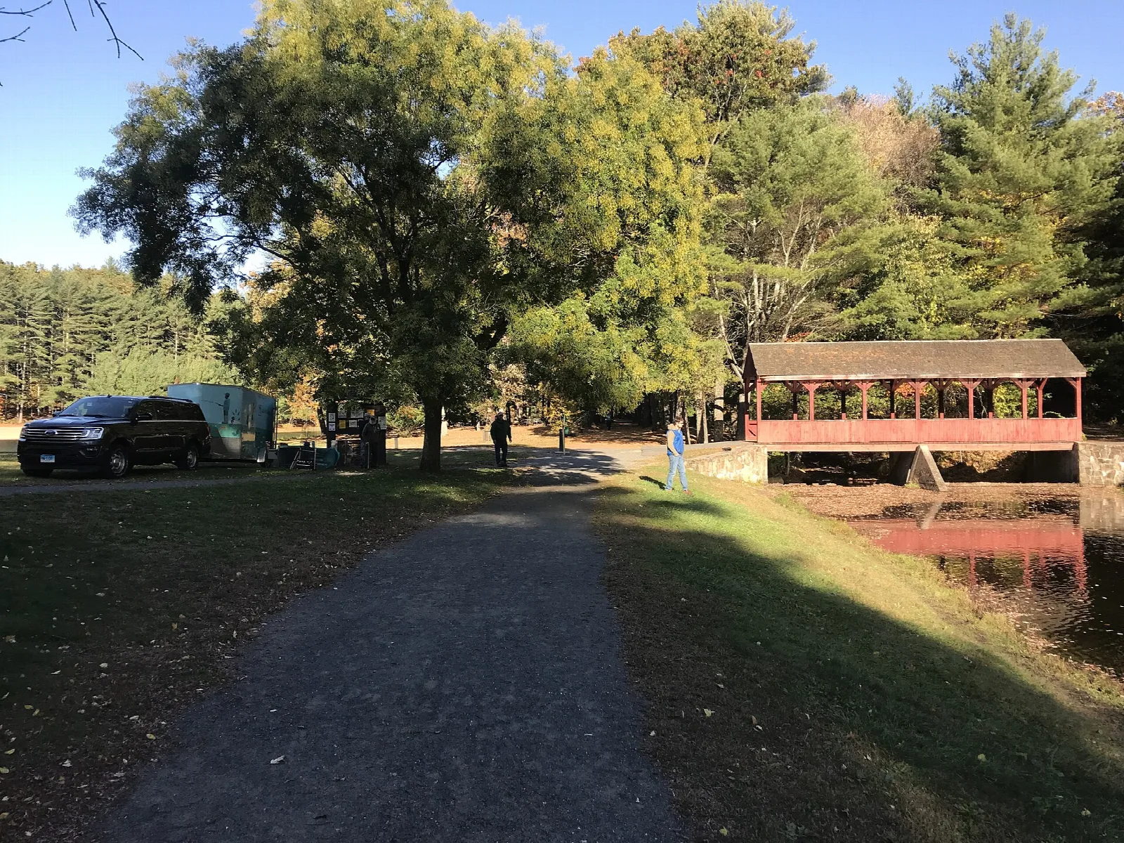 Gravel path leading toward a covered bridge and pond