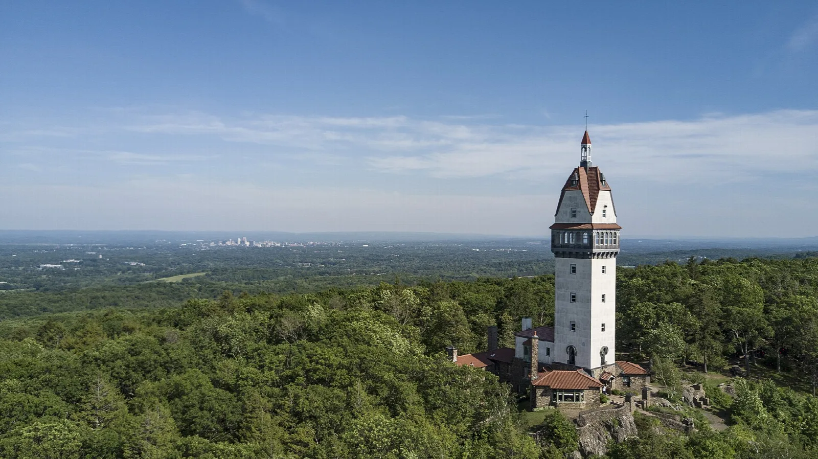 White stone tower on a hilltop over green forest