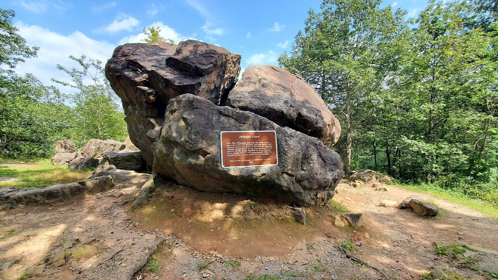 Large boulder with a sign on a dirt clearing