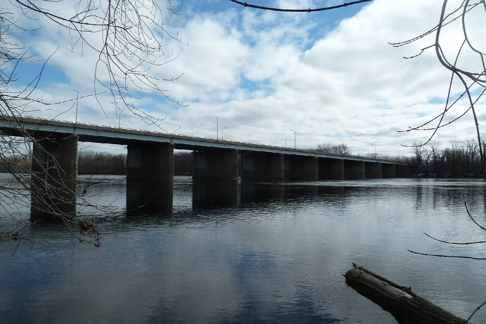 Long bridge crossing a wide river under clouds