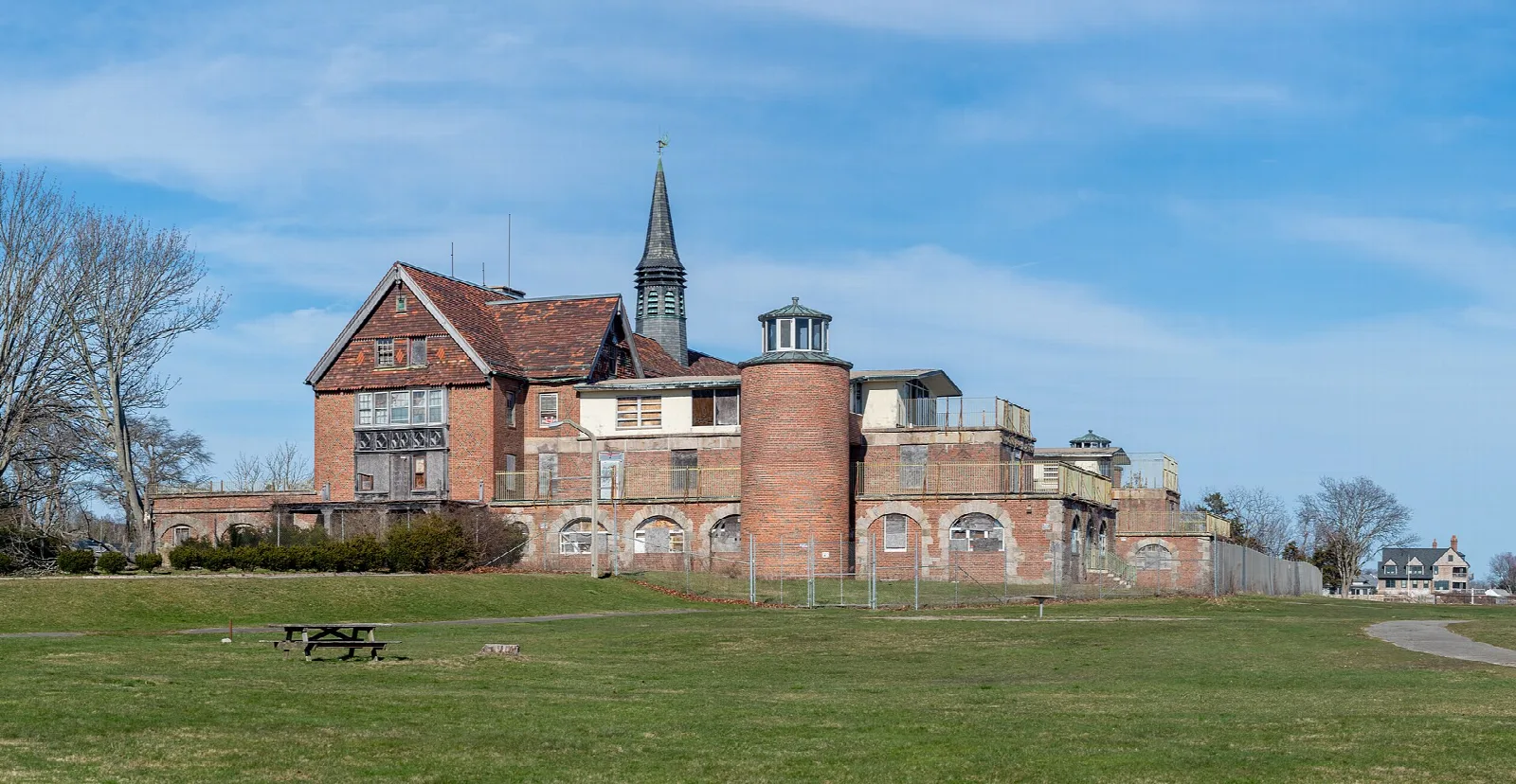 Red brick building with towers and a spire across a lawn