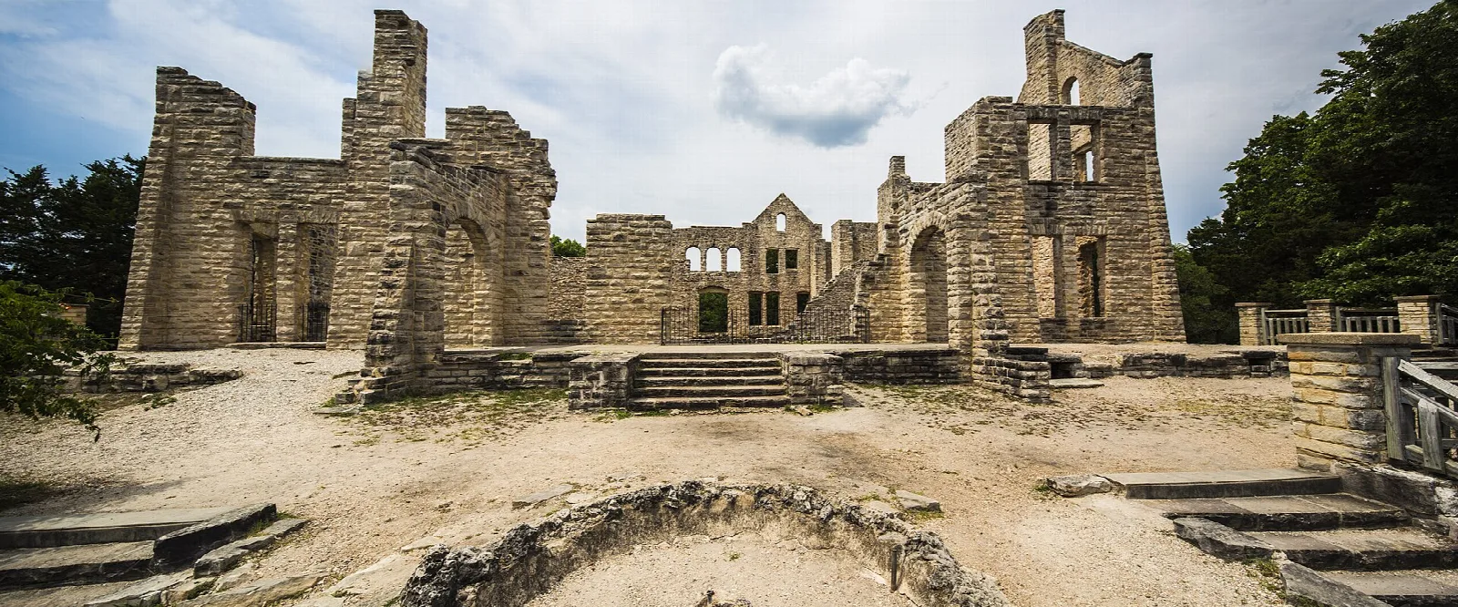 Wide view of the roofless stone castle ruins under a partly cloudy sky