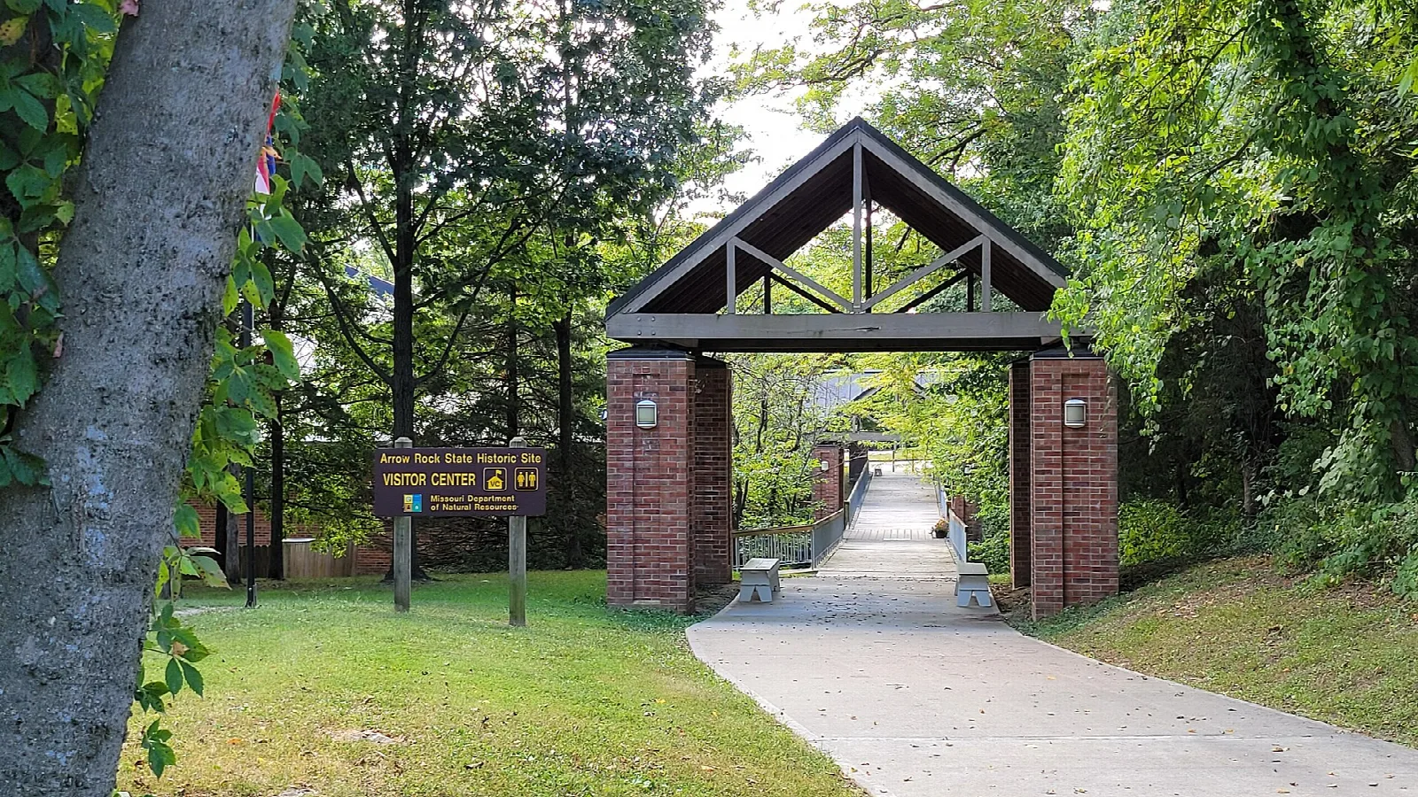 Brick and timber gateway at the end of a paved walkway into the visitor center area