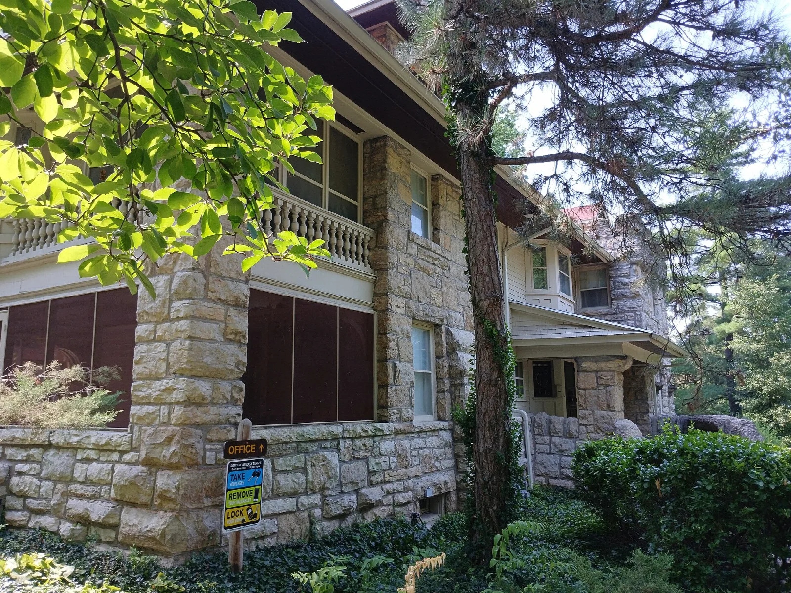 Stone base and porch of the house with leafy trees overhead