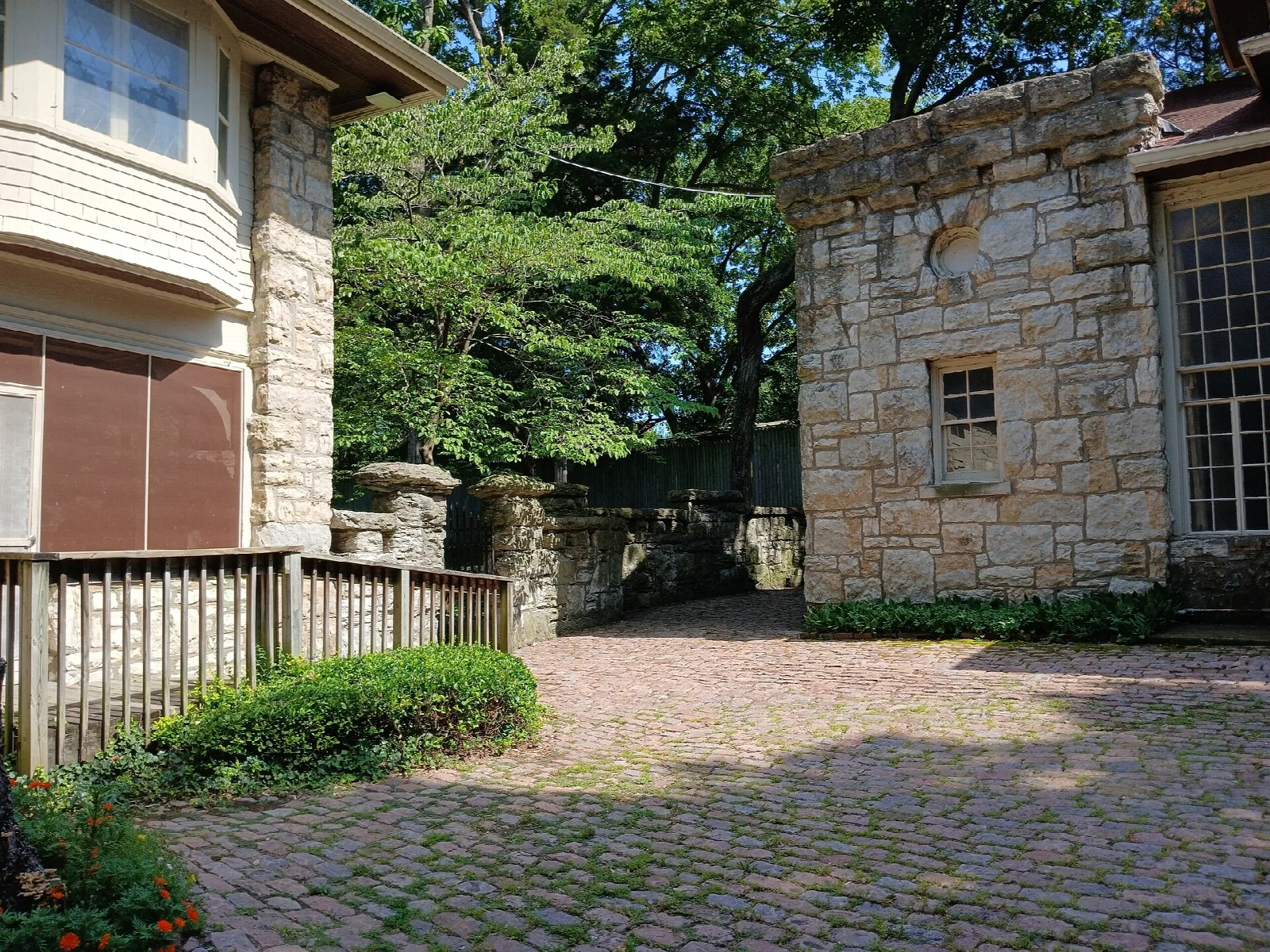 Stone house corner and stone carriage house beside a cobbled drive
