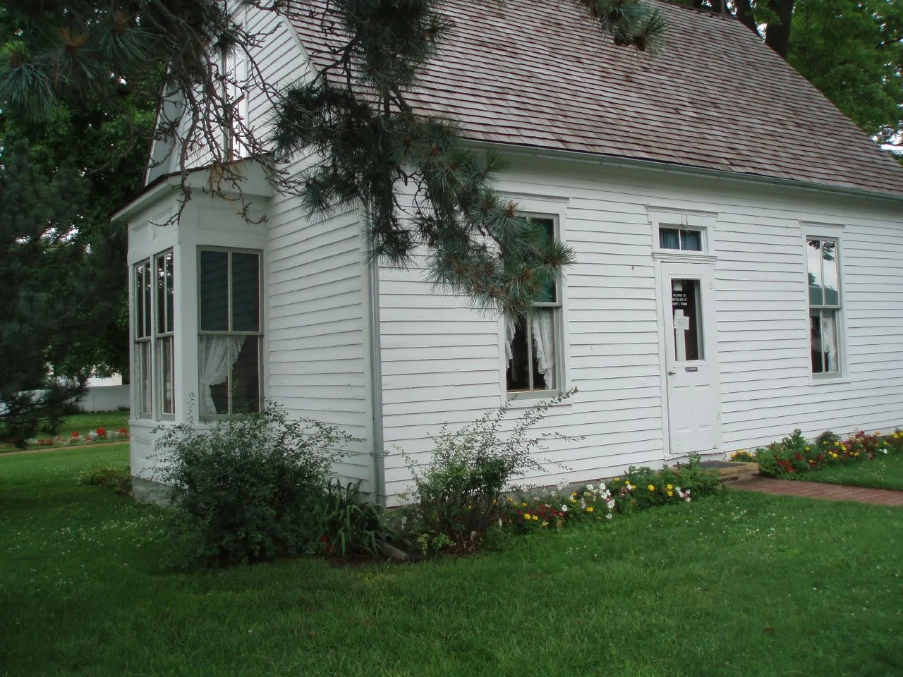 Small white frame house with shrubs on a green lawn