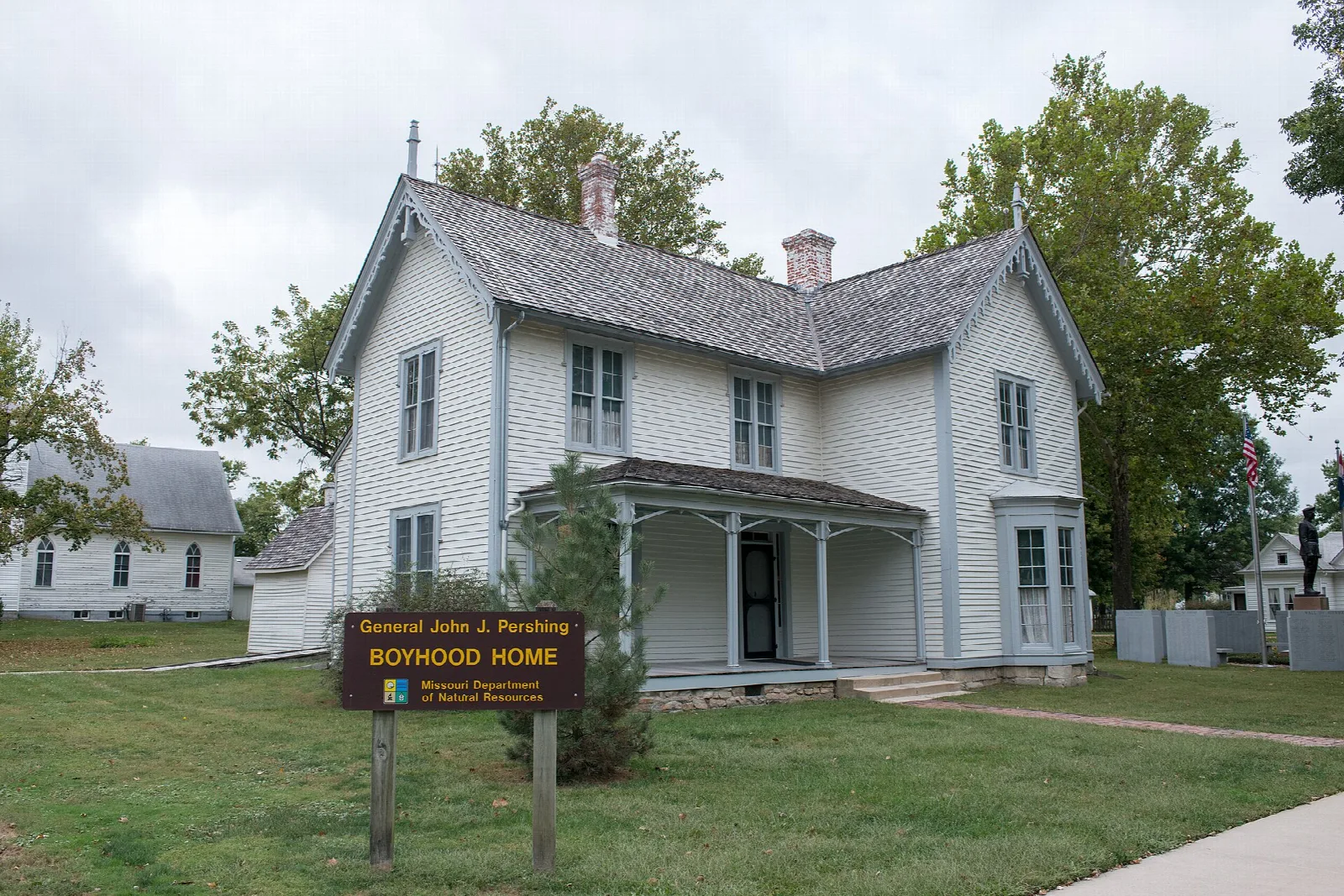 White frame house with a front porch and an information sign in the yard