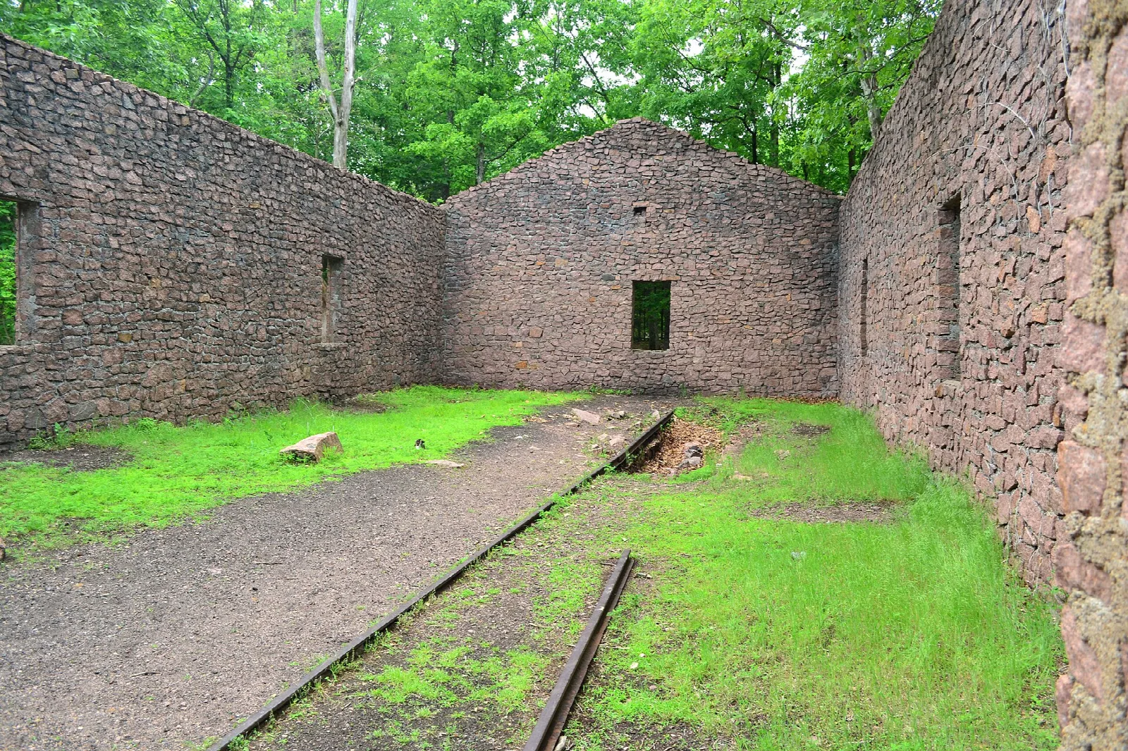 Roofless stone engine house ruin with a rail track running through it
