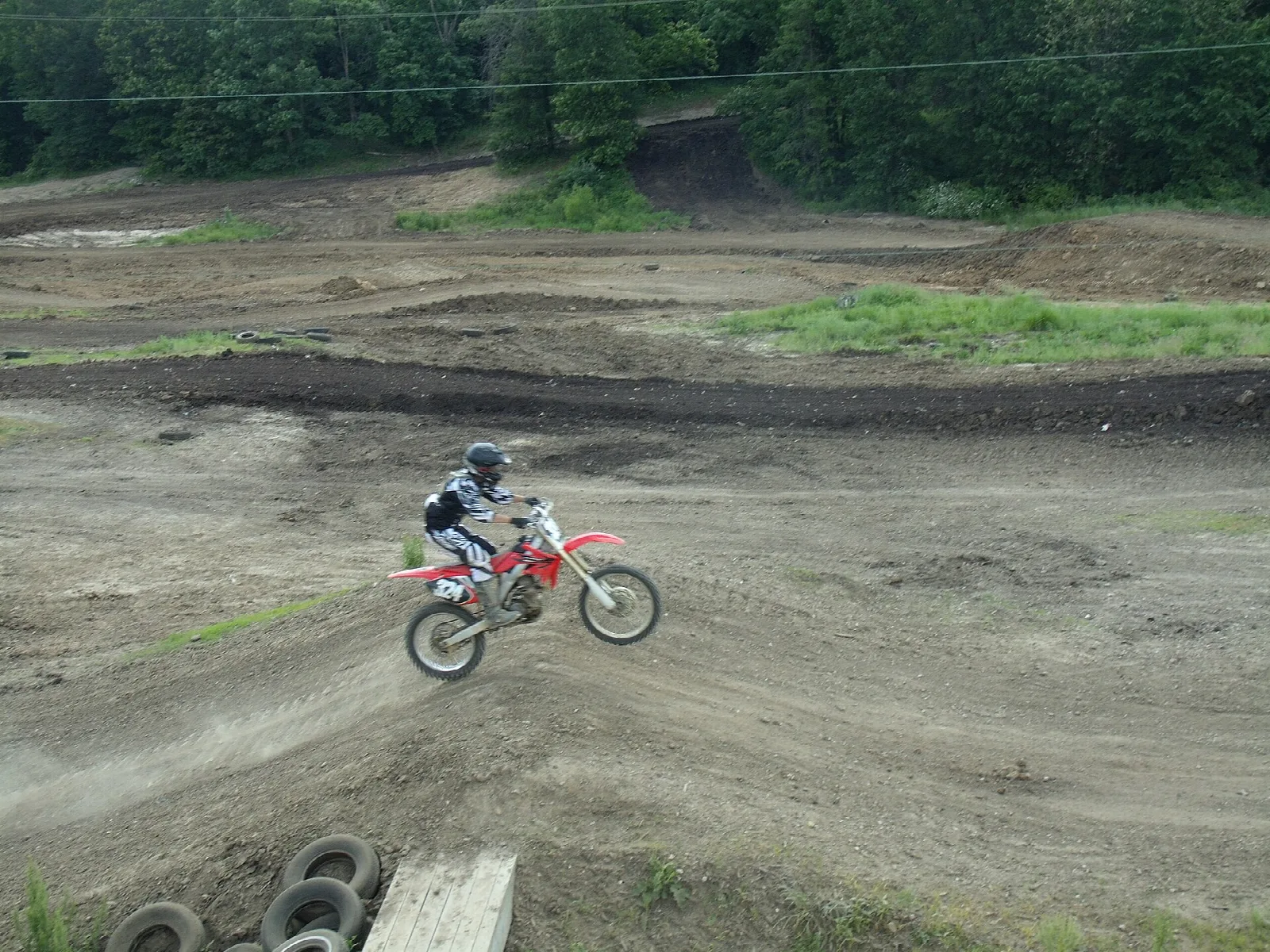 Dirt bike rider jumping on a bare dirt riding area
