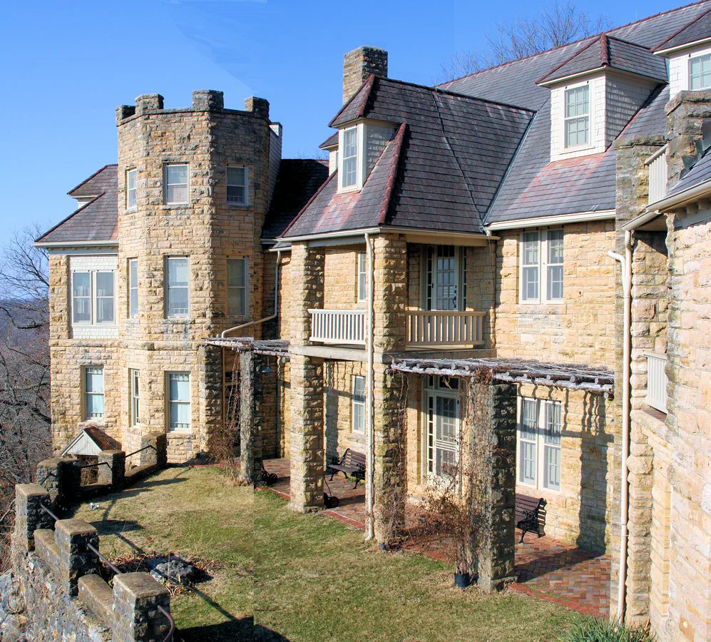Stone lodge with a tower, steep roofs and dormers under a blue sky