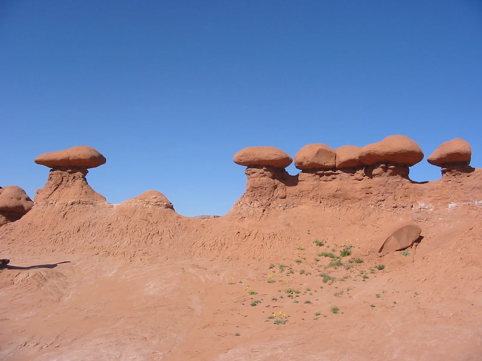 Red sandstone hoodoos with mushroom-shaped caps against a blue sky