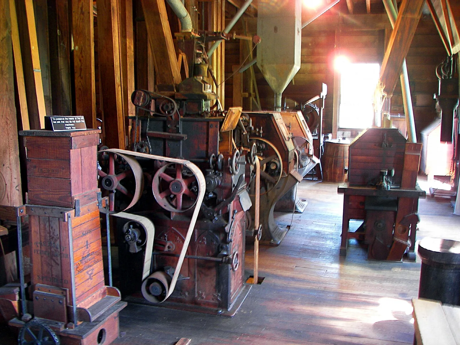 Old milling machinery with belts and pulleys in a sunlit room