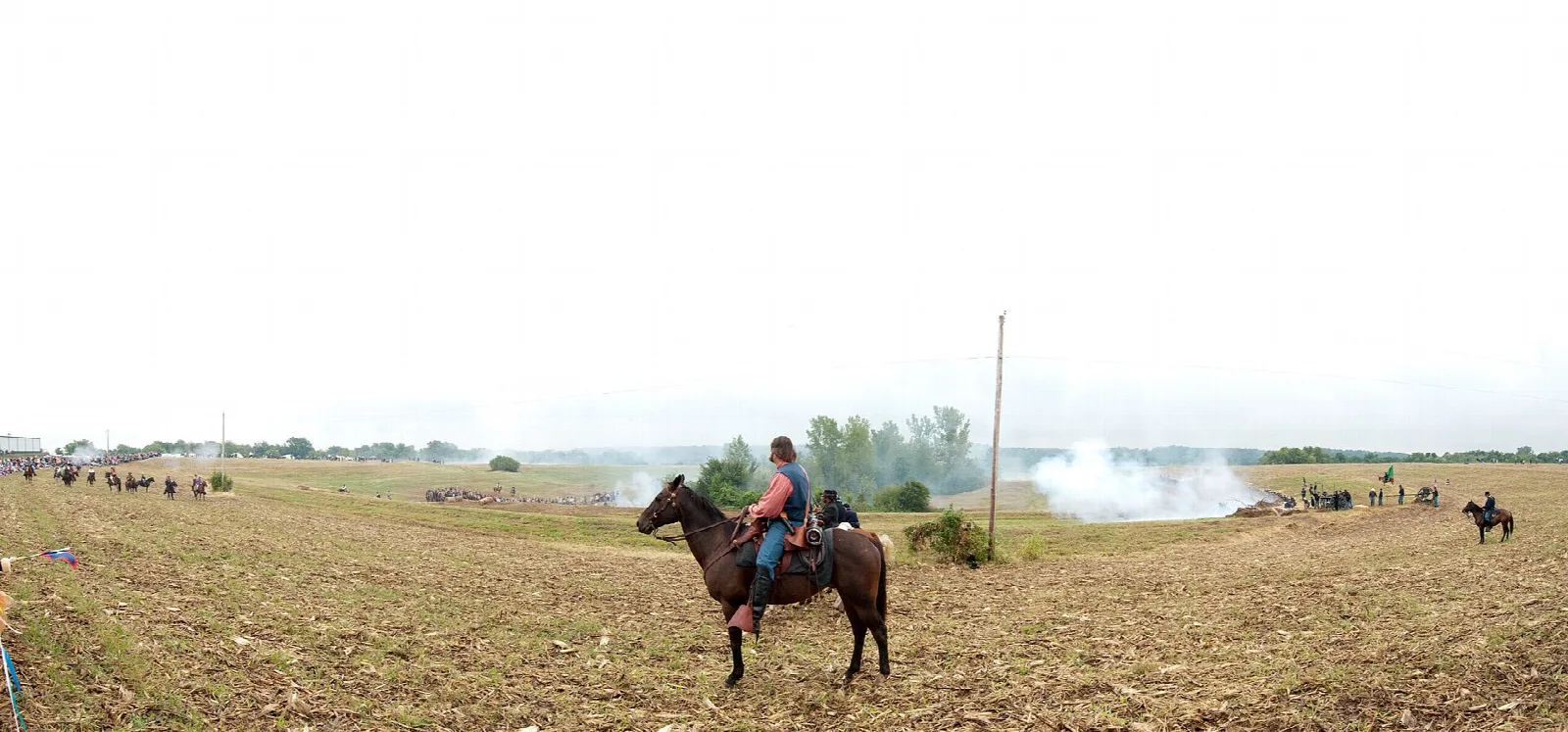 Rider on a horse in an open field with smoke in the distance