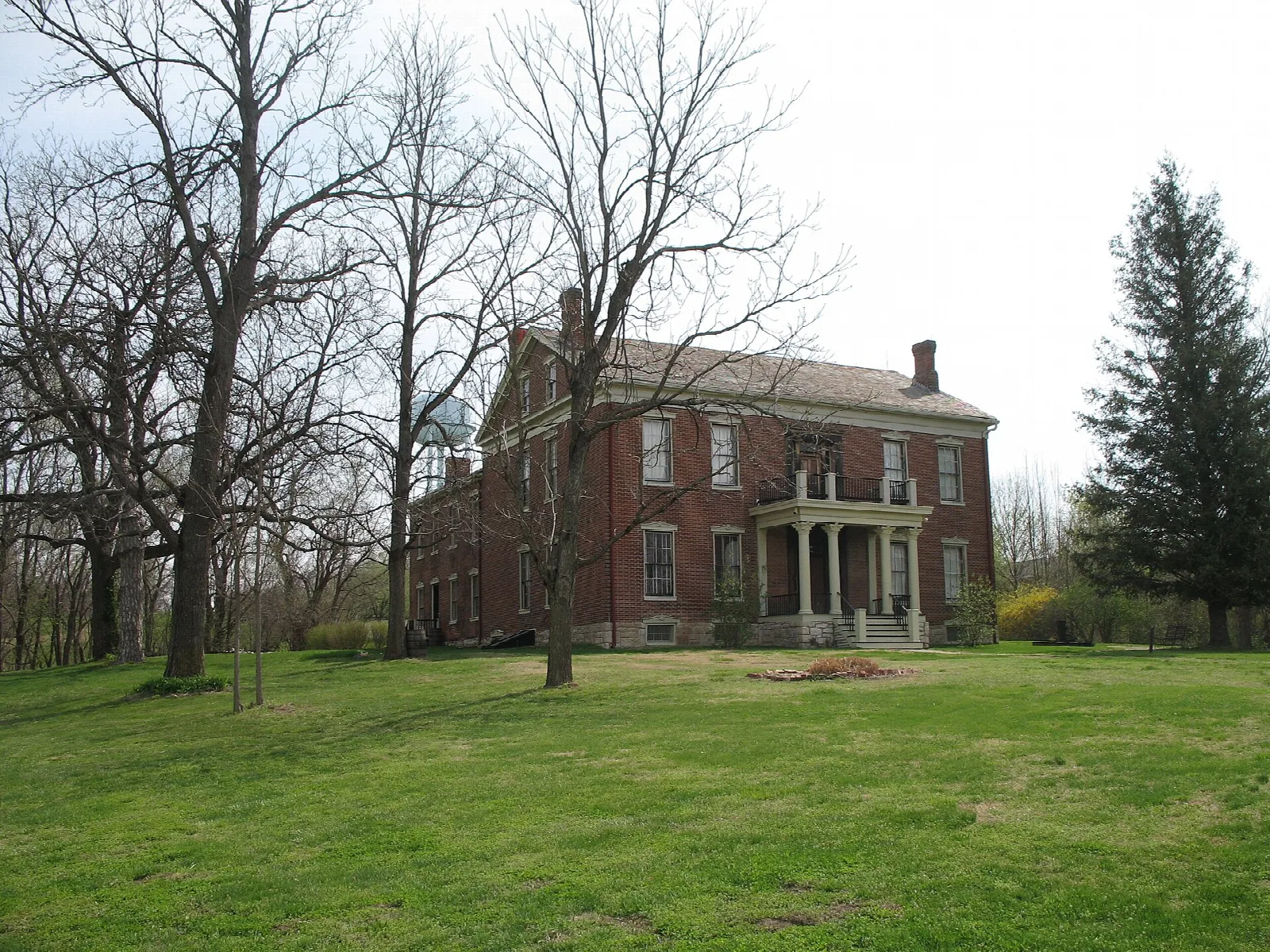 Brick house with a columned porch on a wide lawn with bare trees