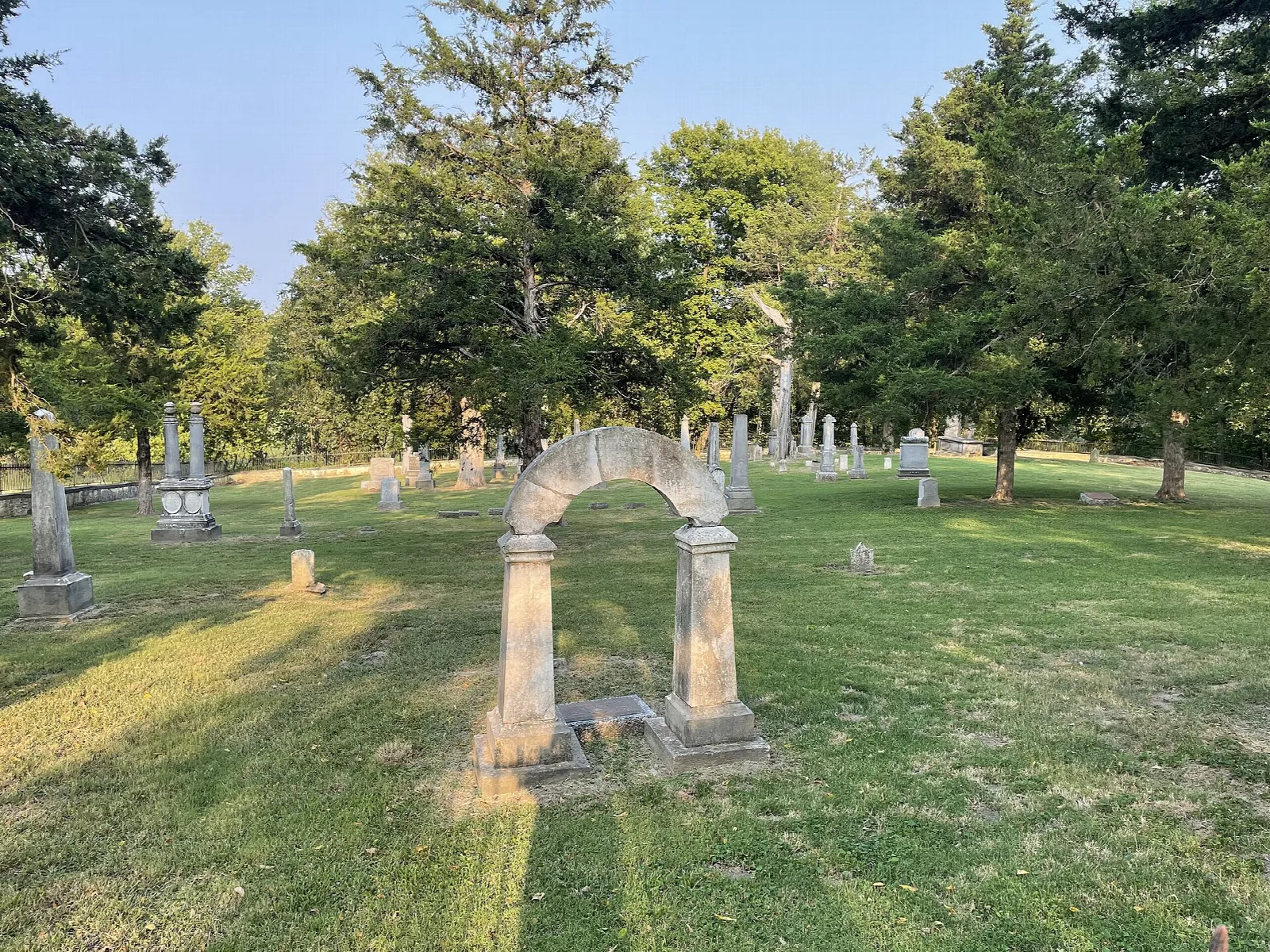 Stone arch among old headstones and tall trees