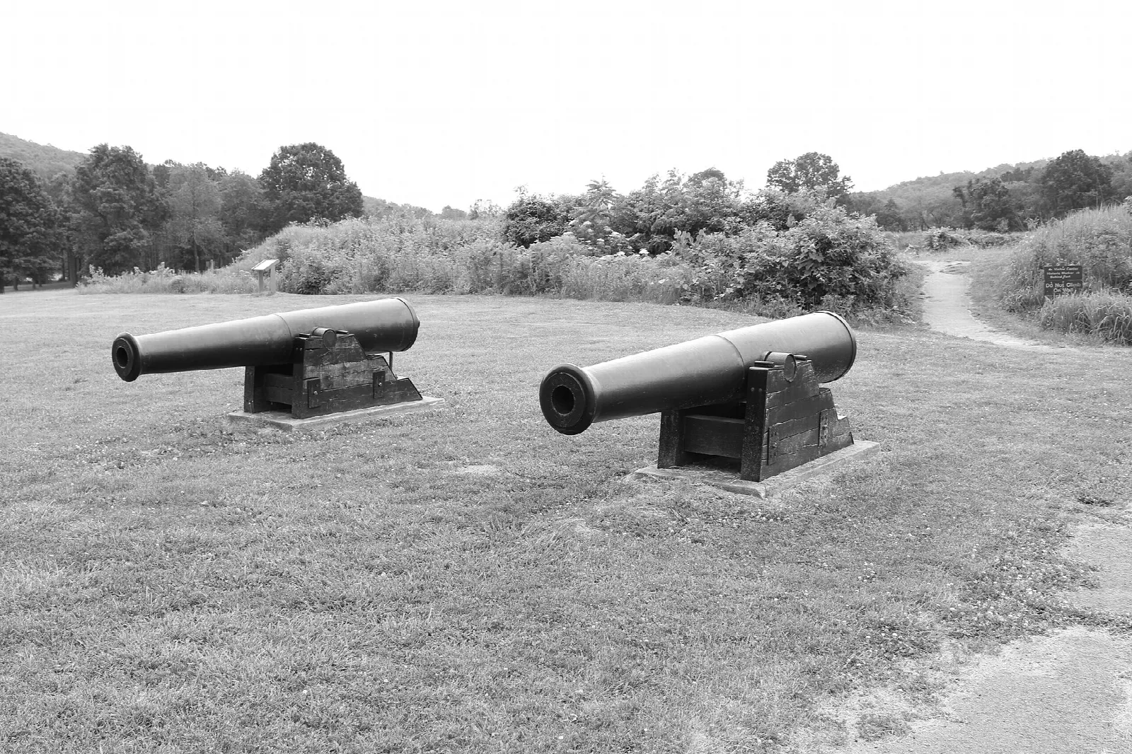 Two cannons on a mown earthwork in black and white