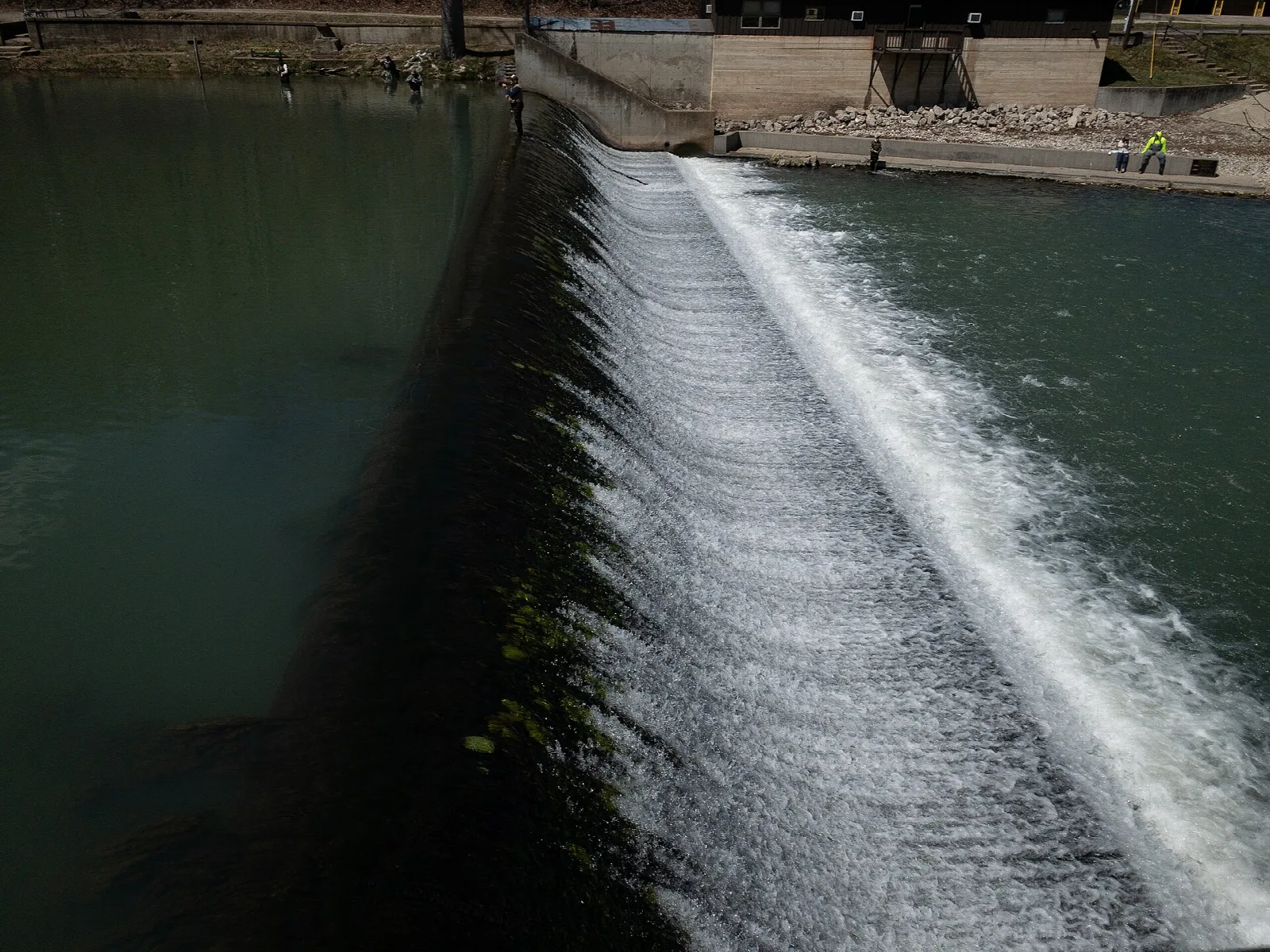 Water pouring down a long angled dam beside a stream