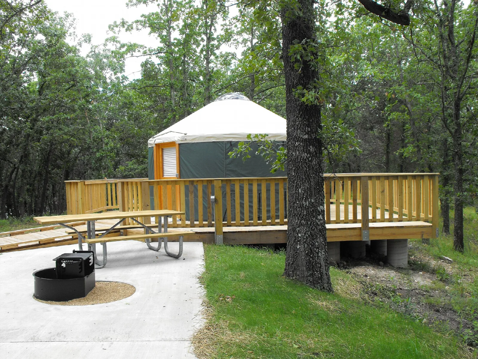Round yurt with a deck and picnic table among trees