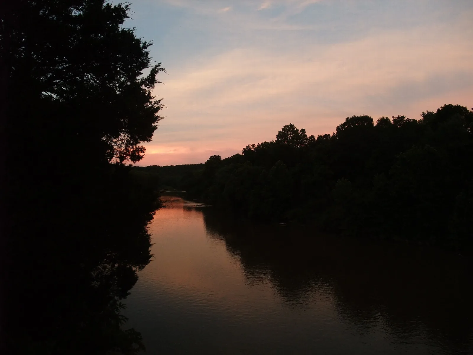 River at sunset with dark tree-covered banks