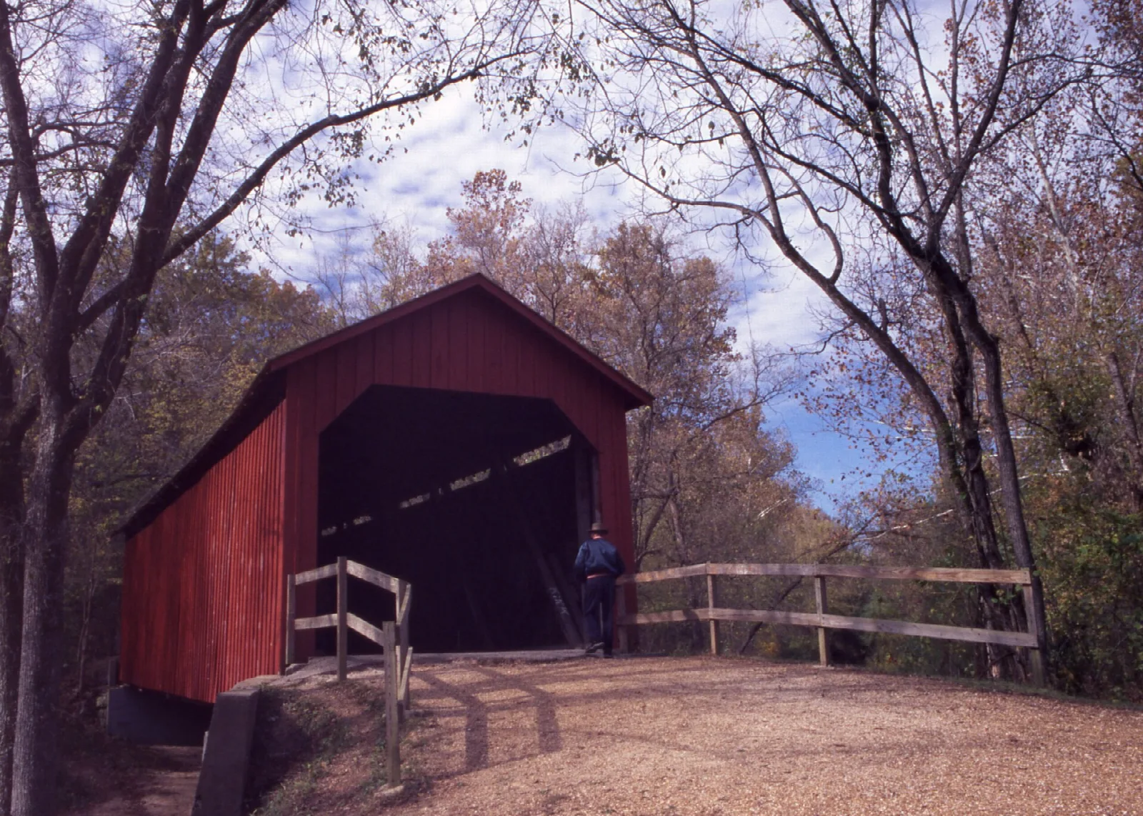 Red covered bridge seen through bare autumn trees