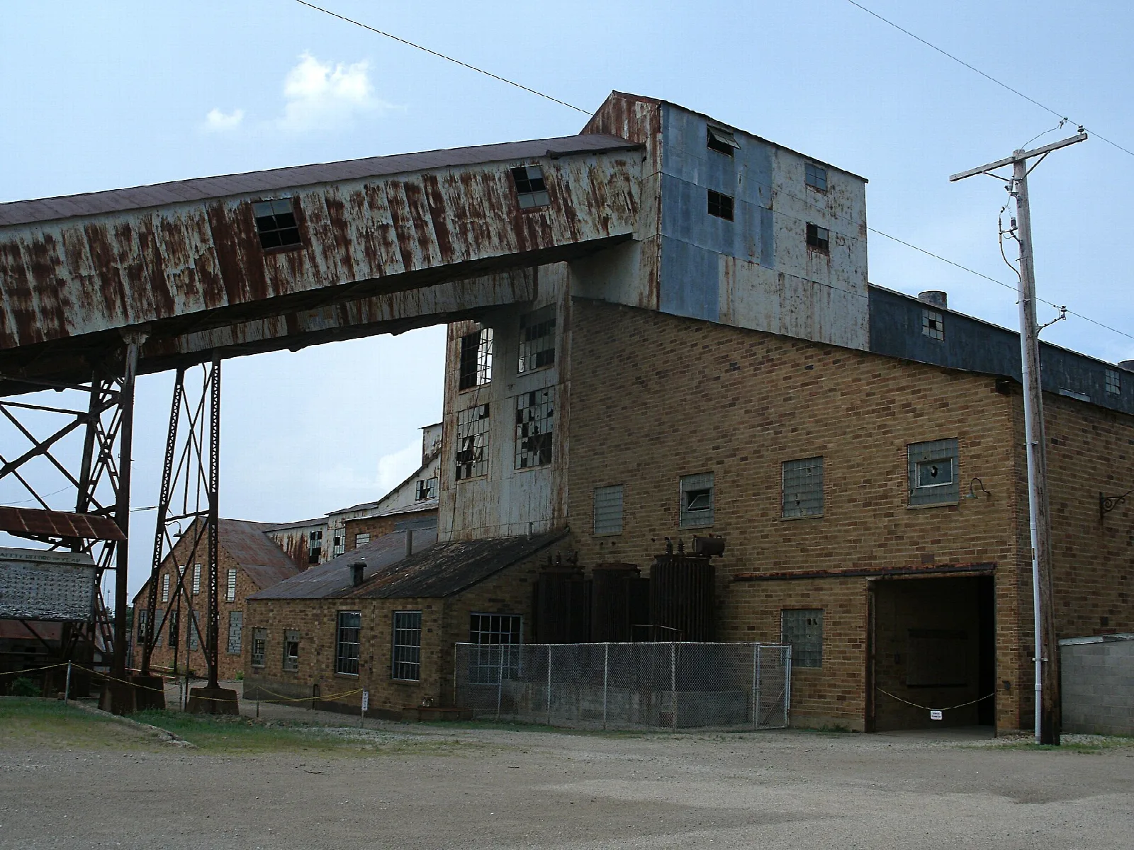 Brick mill building with a rusty elevated conveyor