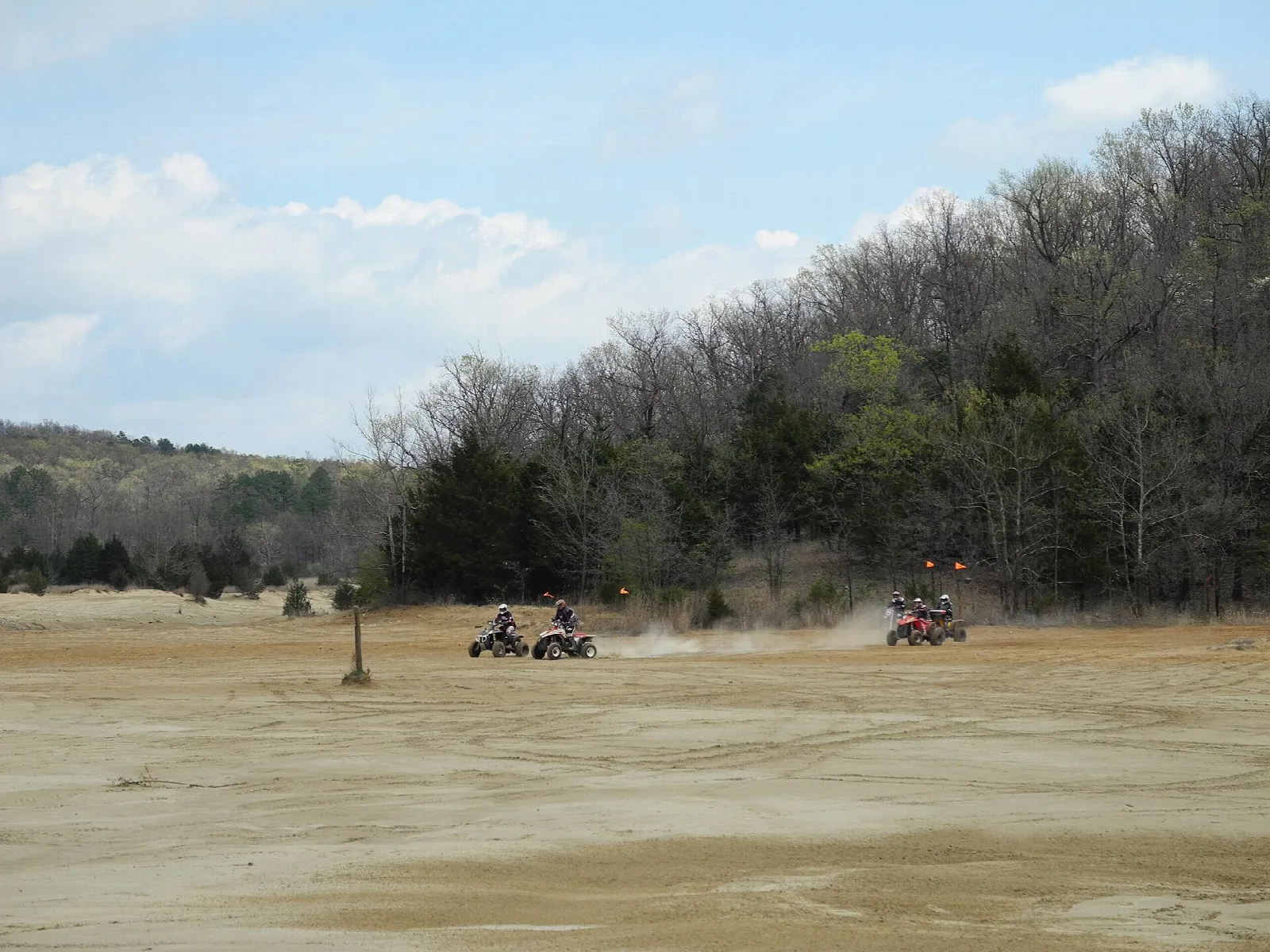 Distant riders kicking up dust on a wide sandy flat