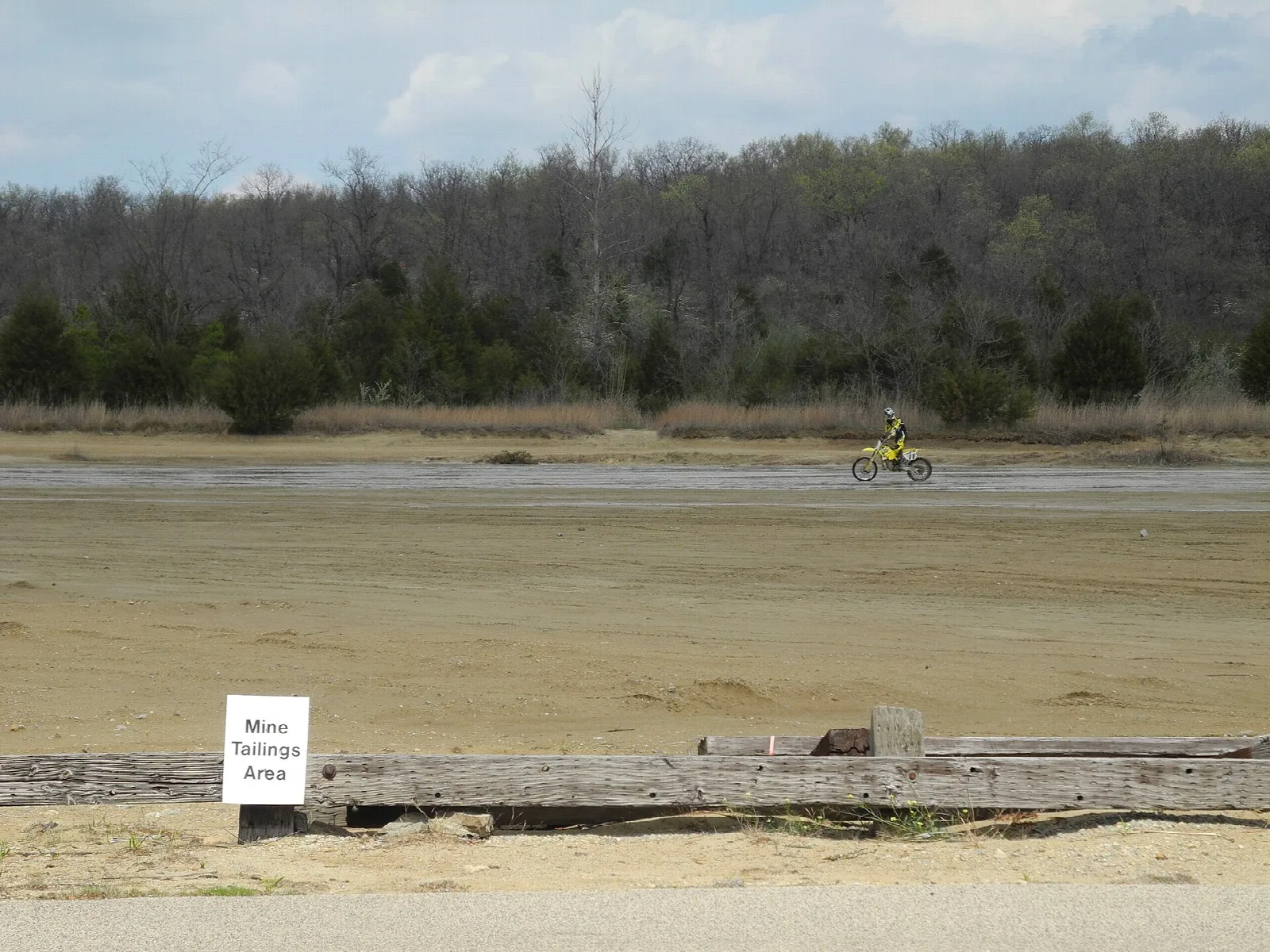 Motorcyclist far off across a broad sandy flat