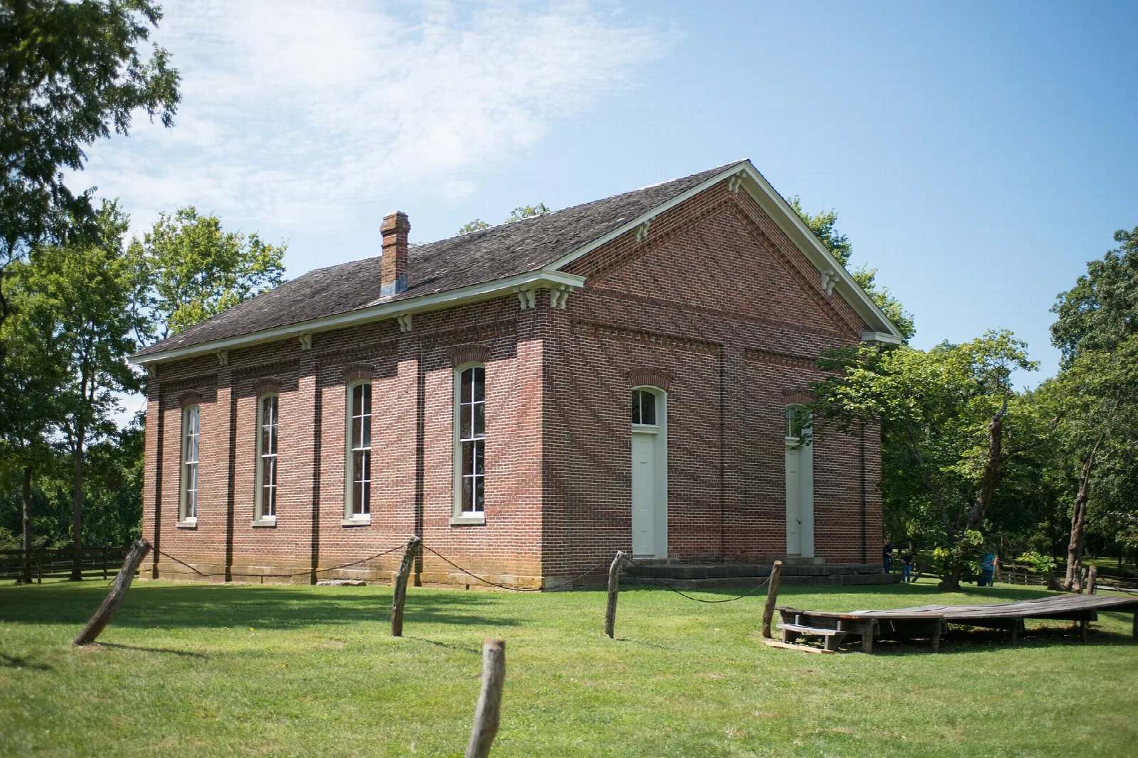 Long brick building with a pitched roof on a green lawn