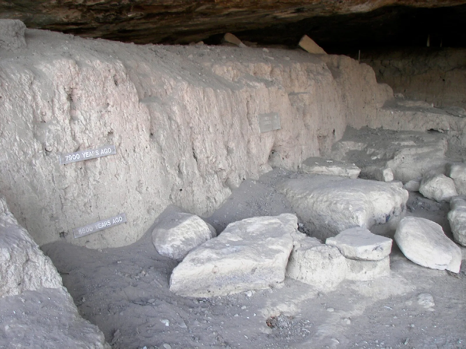 Inside the cave, a layered excavated floor with large pale rocks