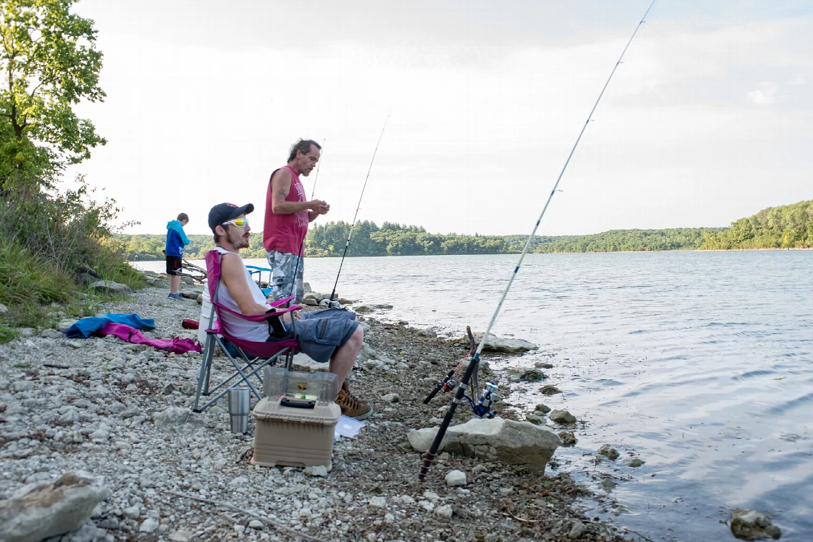 Anglers fishing from a rocky shore with the lake behind