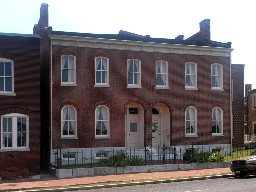Two-story red brick row house with arched doorways on a city street