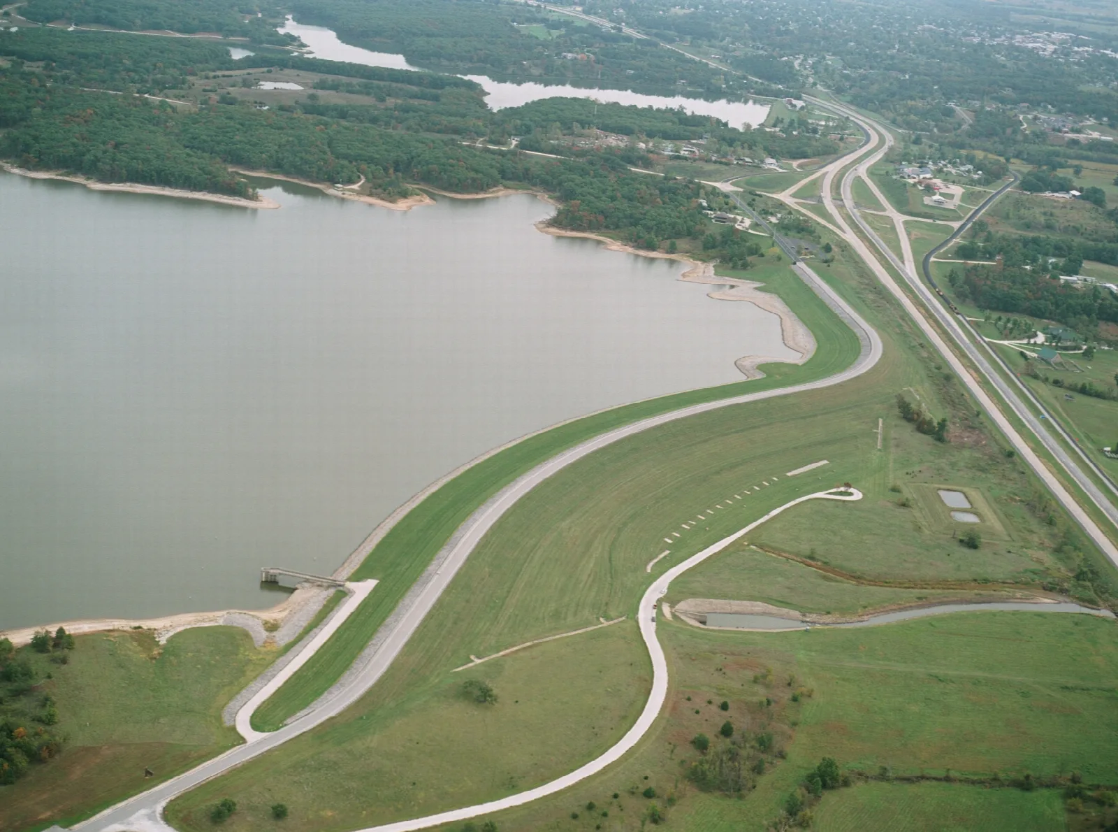 Aerial view of a lake, earthen dam and winding road