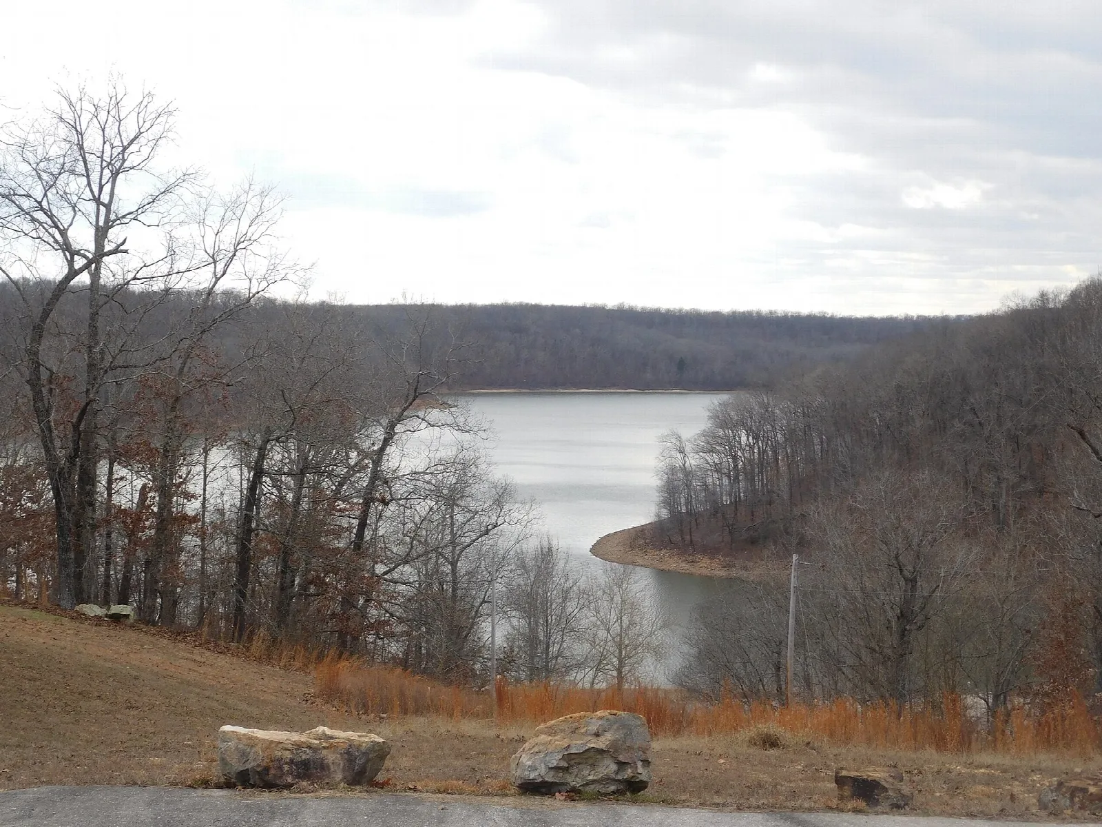Lake cove with bare trees and rocks in the foreground